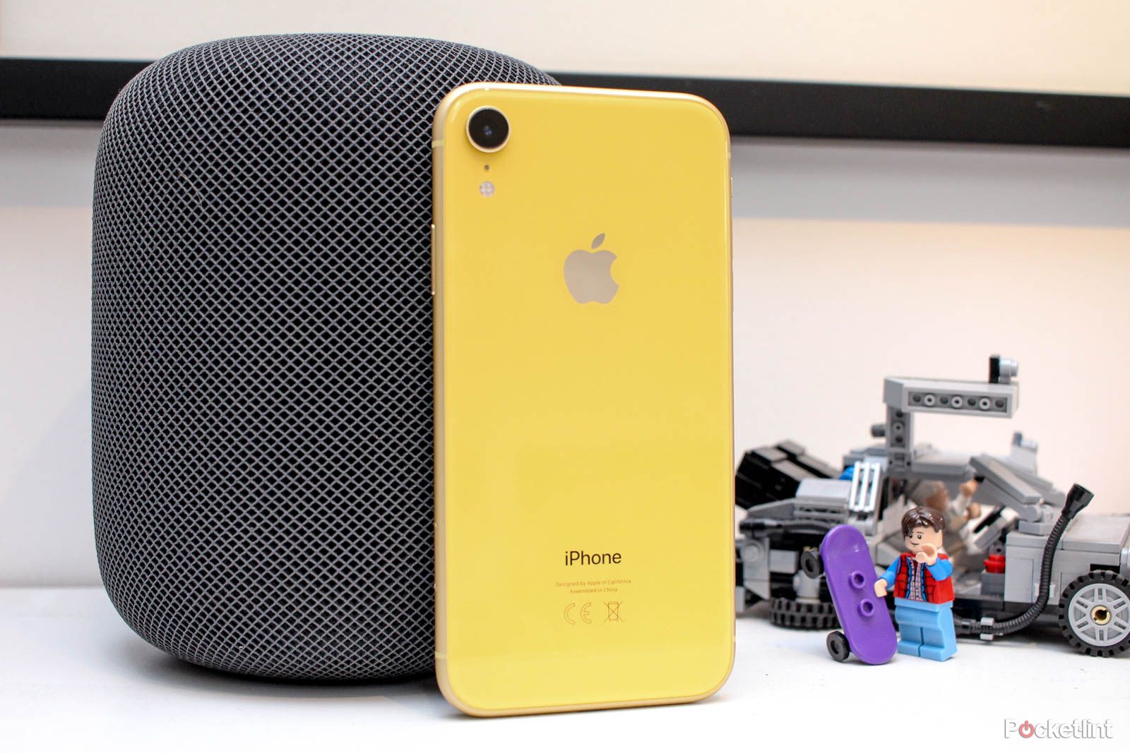 Yellow iPhone XR leaning against a black HomePod