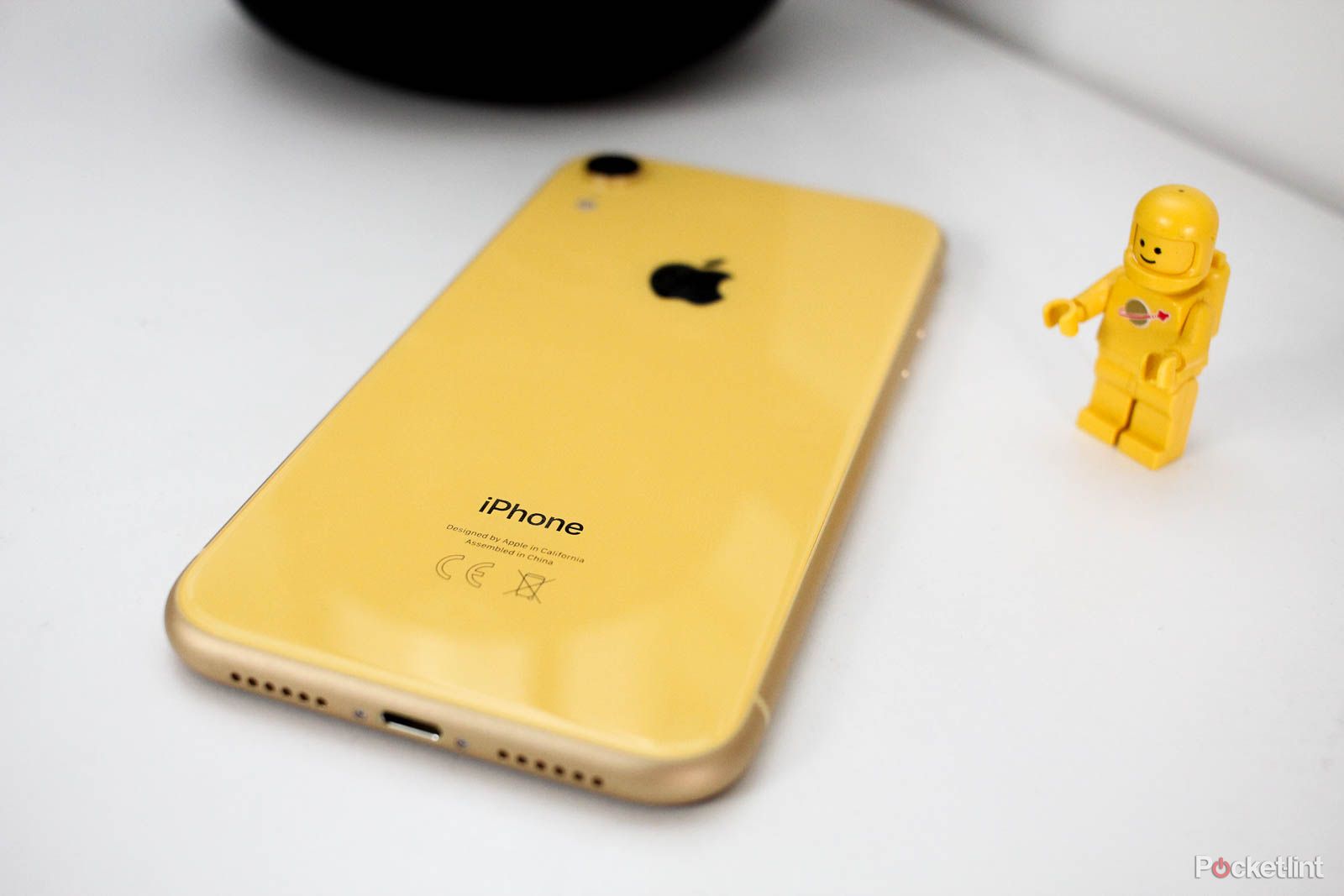 iPhone XR in Yellow pm a white desk with yellow lego man