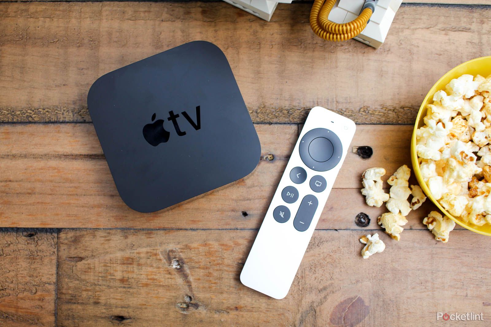 Apple TV and remote on wood table with popcorn