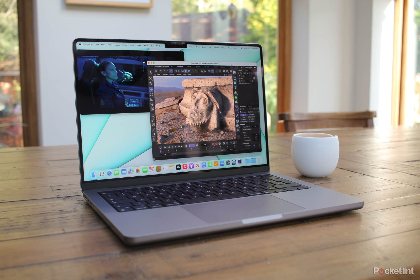 14-inch MacBook Pro open on wooded table beside cup
