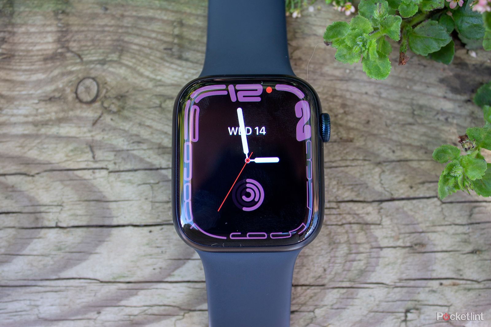 Apple Watch Series 8 with black band and purple face on wood