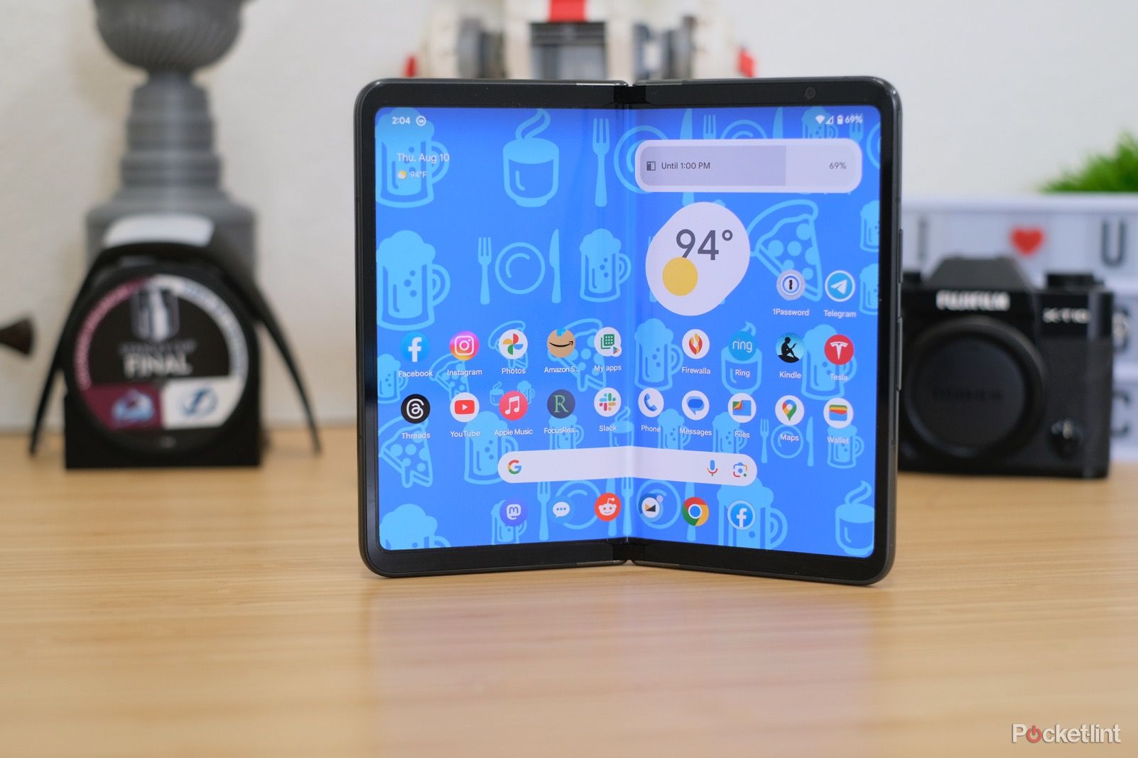 A Google Pixel Fold on a desk with an emoji wallpaper. 