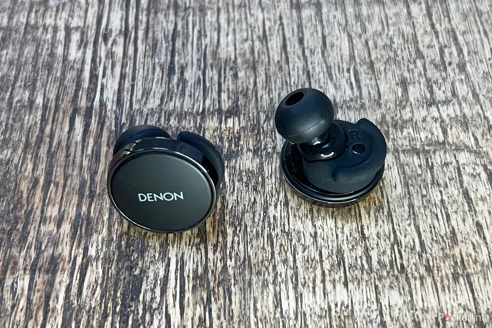 Denon PerL Pro earbuds on wooden table
