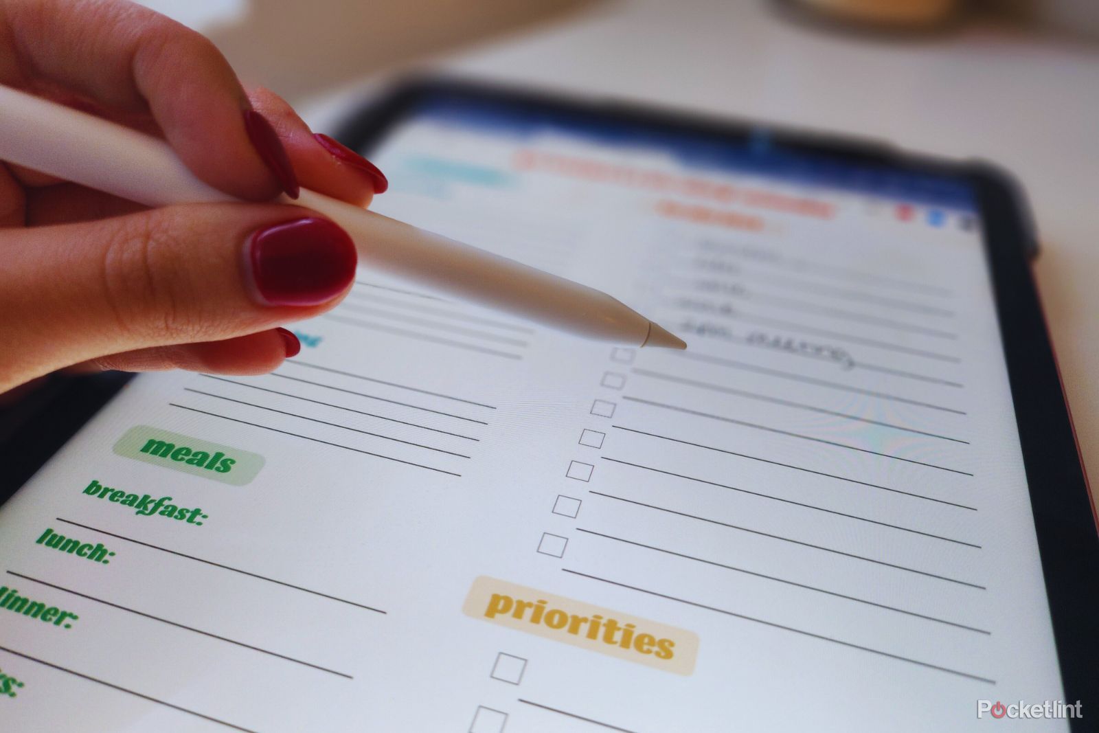 A photo of a hand using a stylus to check off a to-do list on an iPad