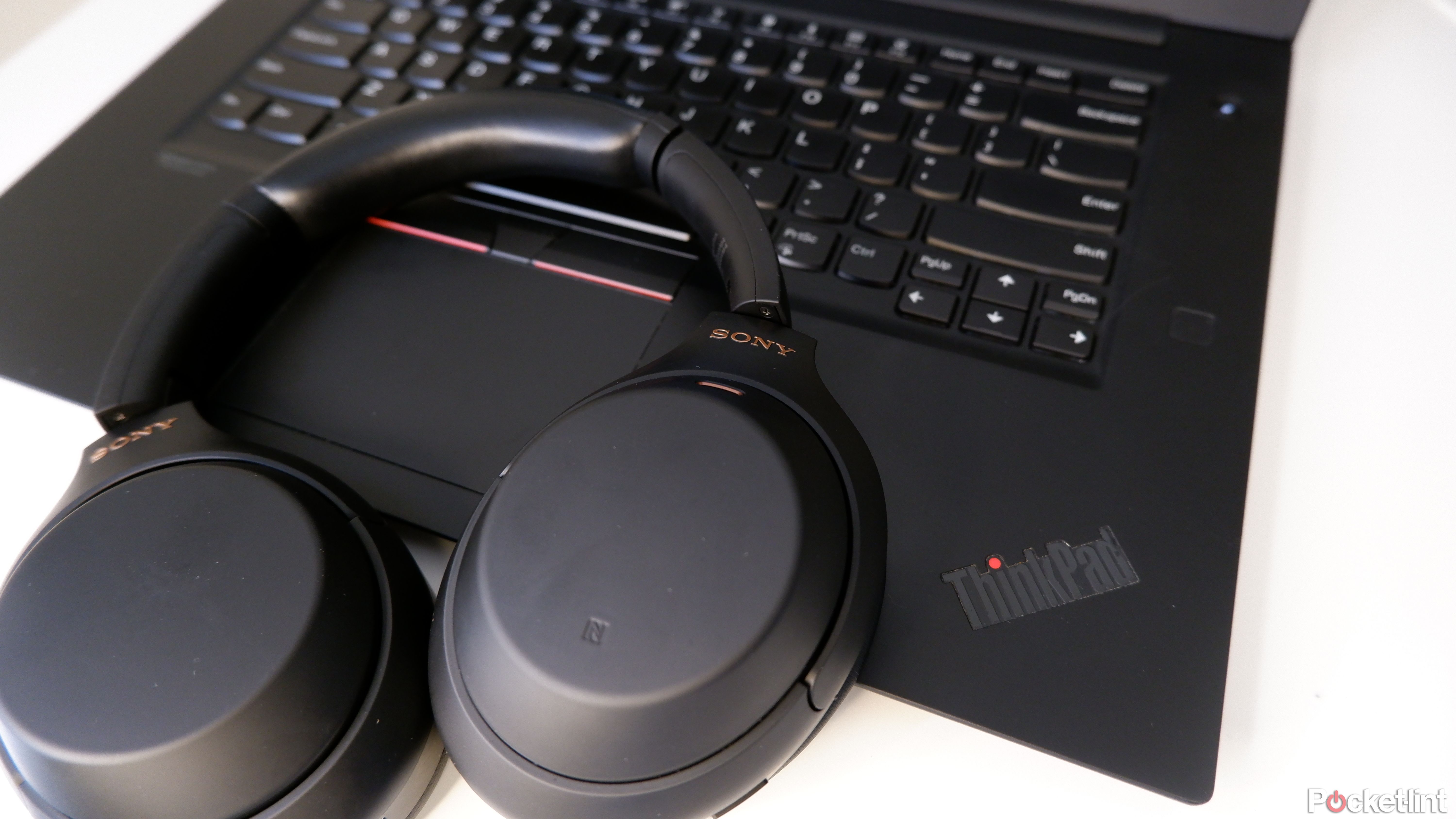 A pair of Sony WH-1000XM4 placed on top of an open ThinkPad.
