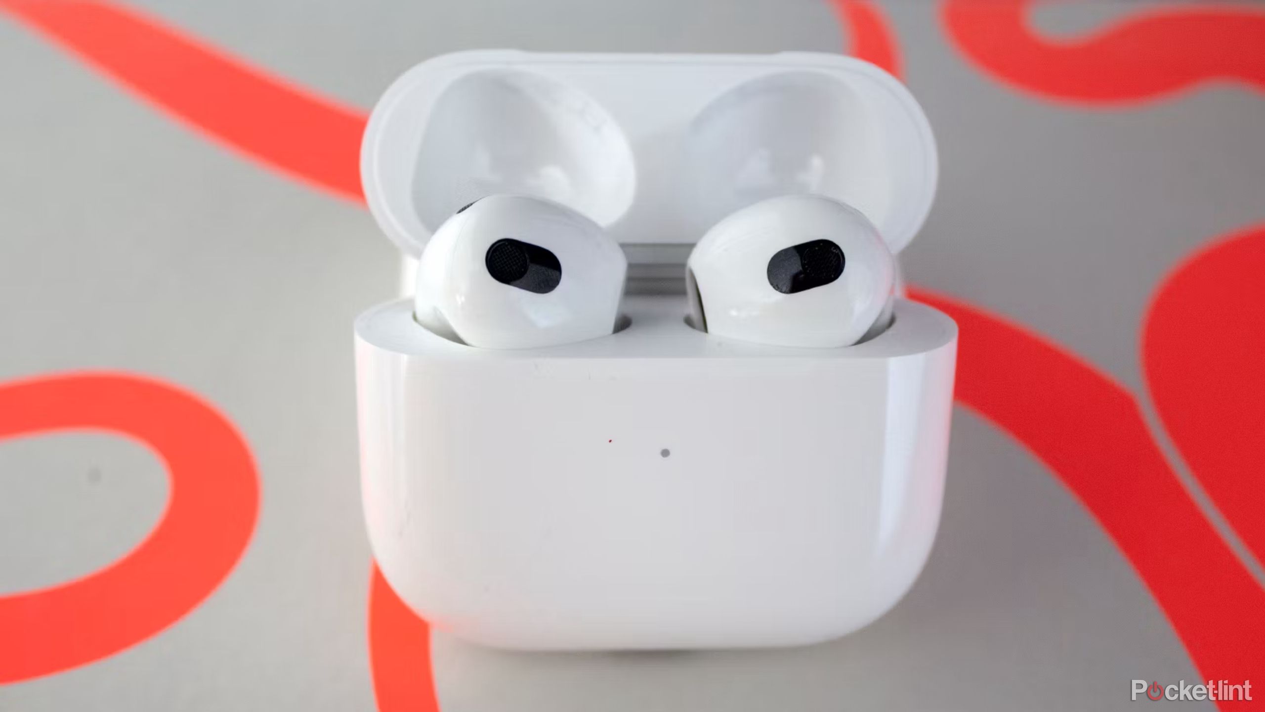 The third-generation AirPods sitting in an open charging case on a colorful background.