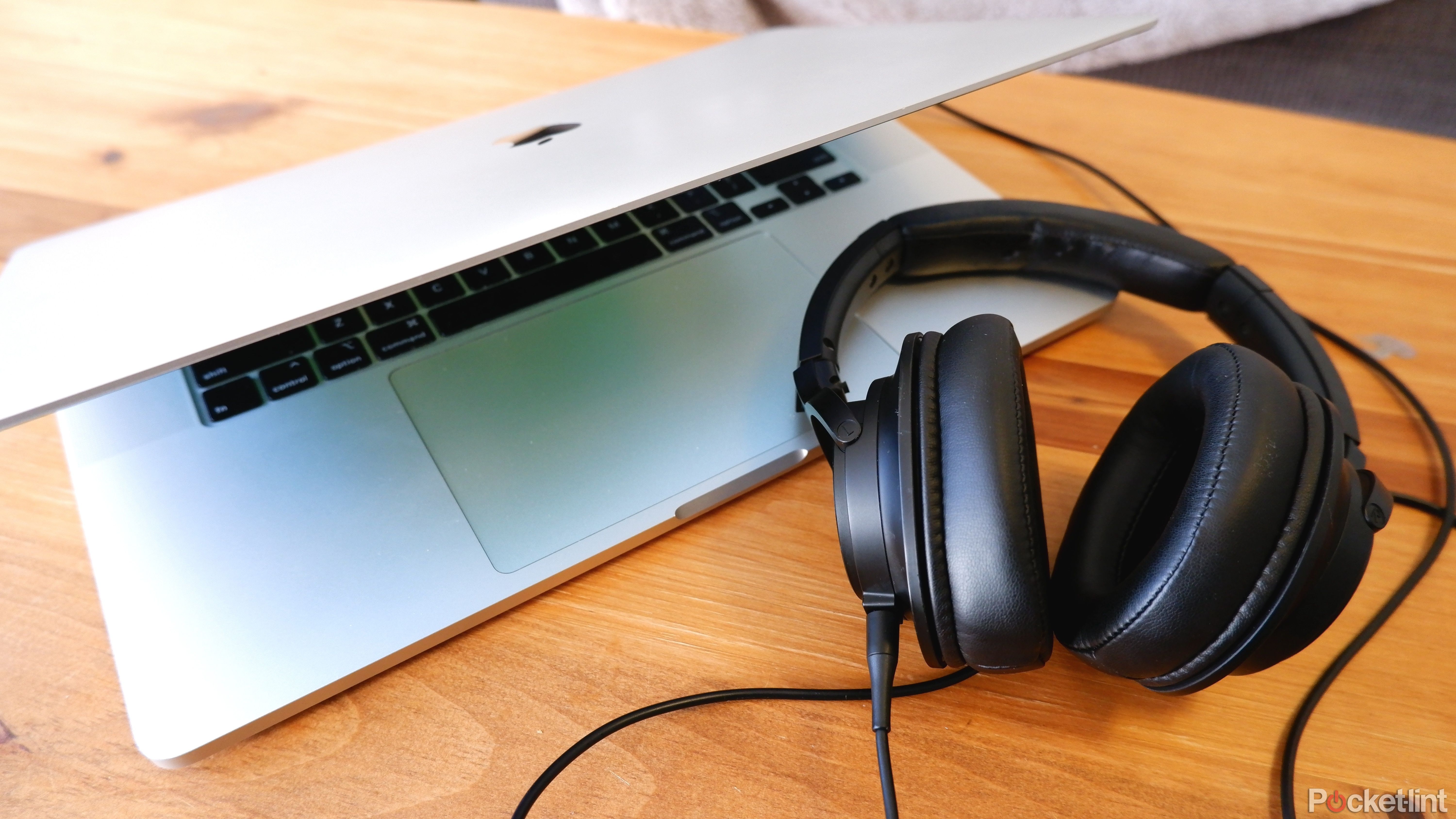 A pair of Audio-Technica ATH-SR50 plugged into and sitting beside a slightly open Macbook Pro.