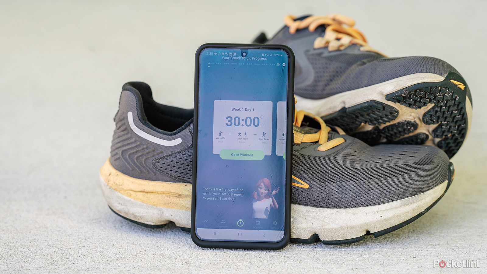 A phone displays the Couch to 5K app while leaning against running shoes. 