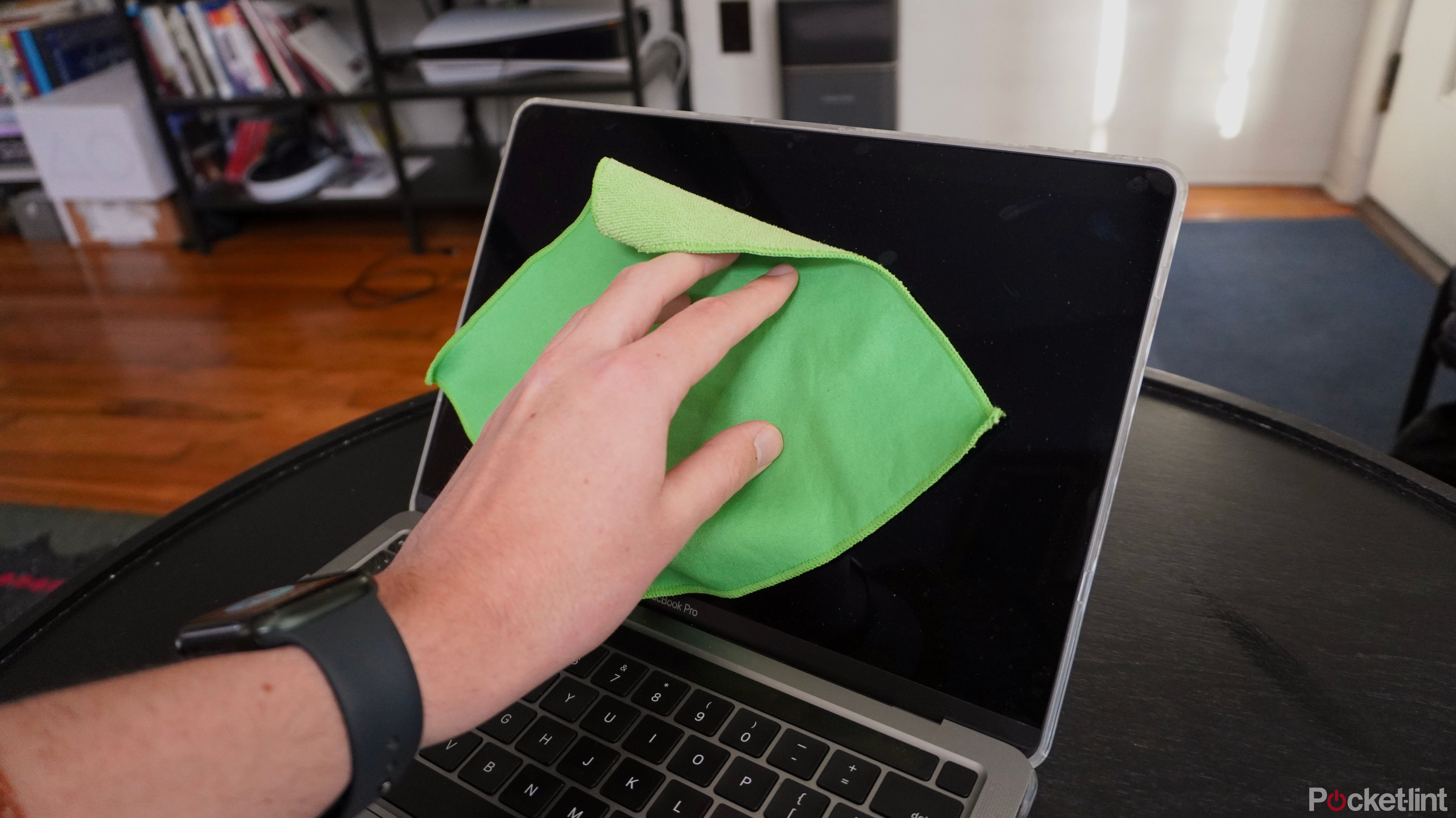 Cleaning a MacBook Pro display with a microfiber cloth.