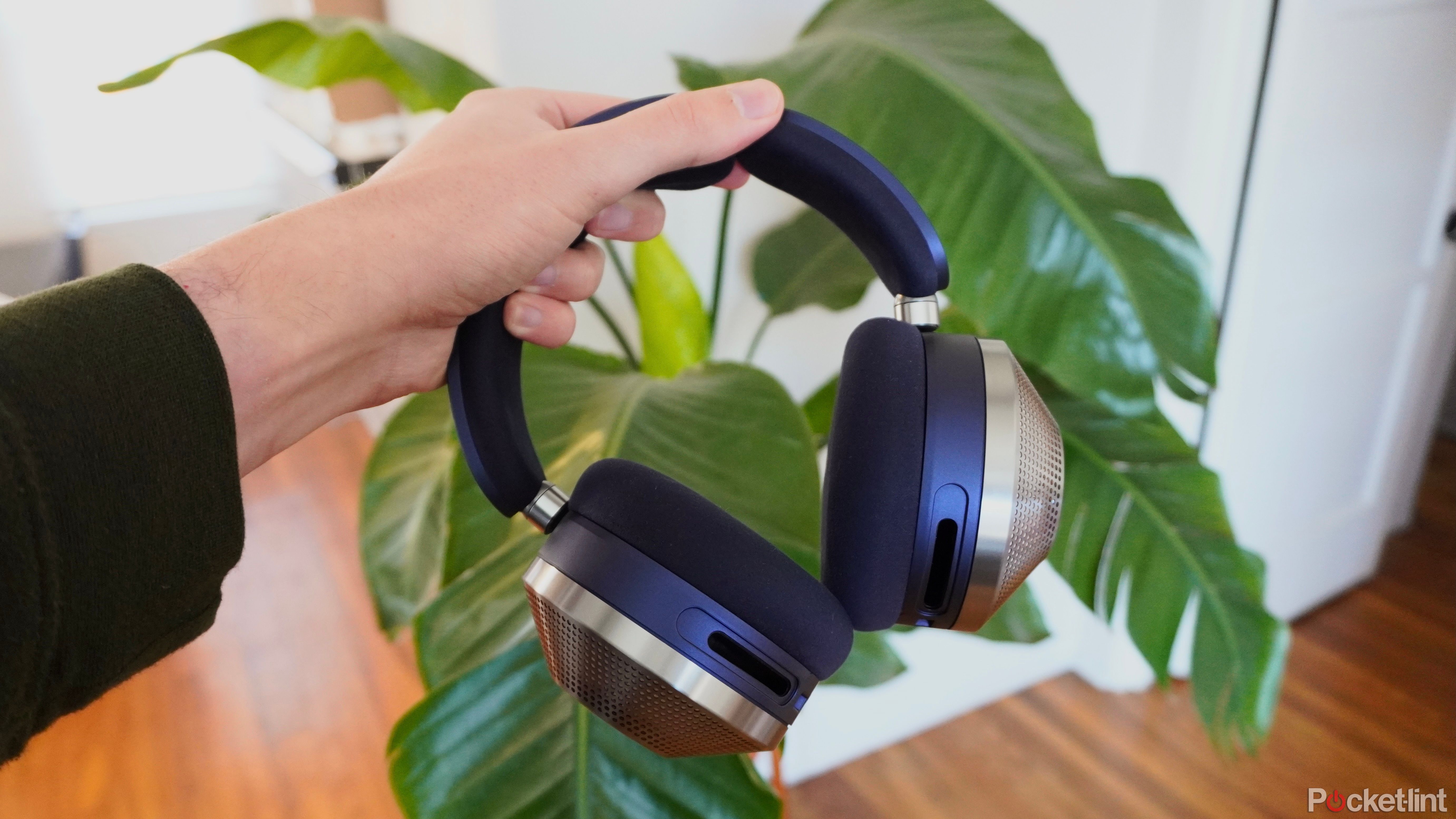 The Dyson Zone headphones being held in front of a potted plant.