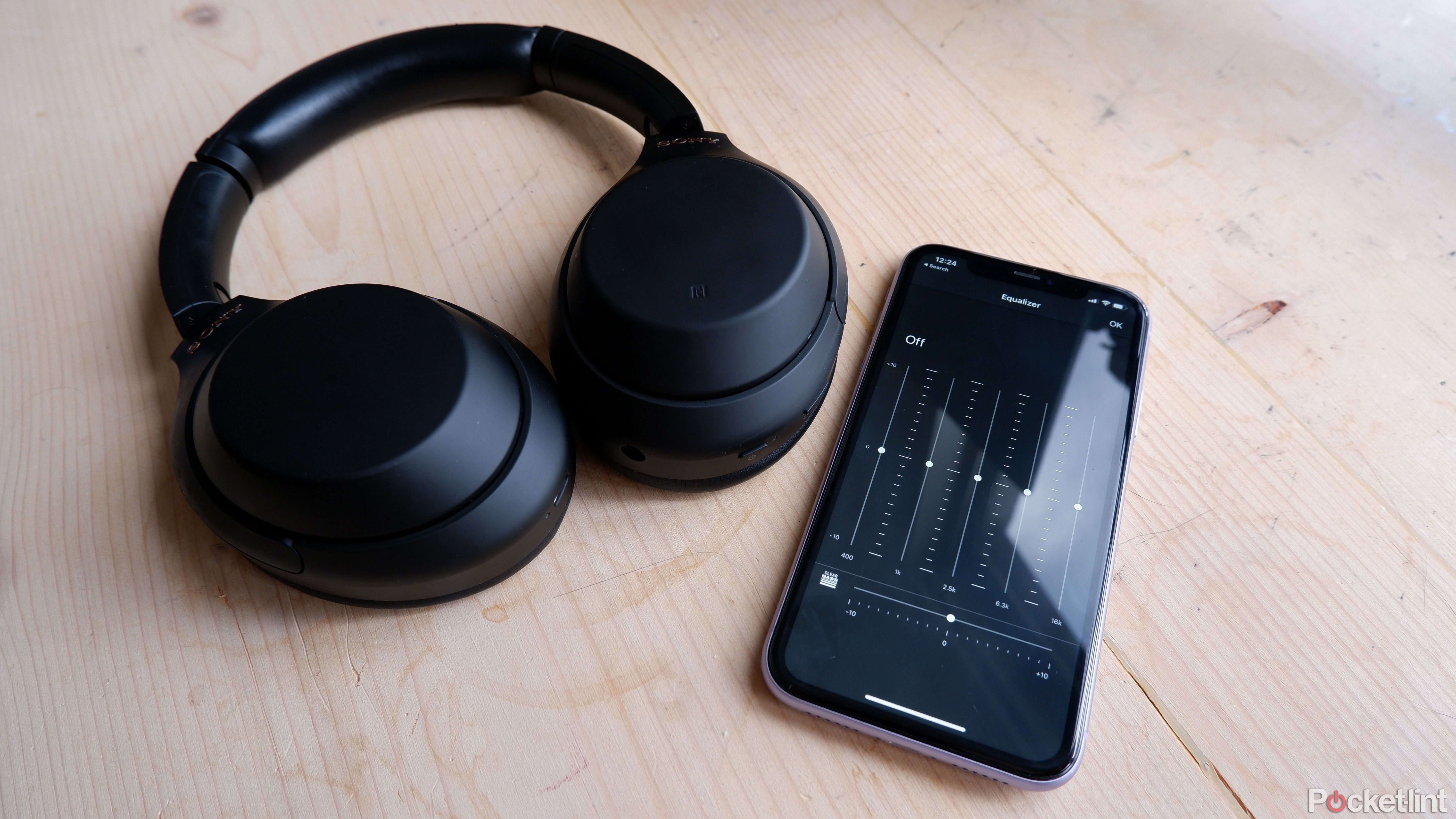The Sony WH-1000XM4 next to a phone with the Sony Headphones app open, showing the equalizer.
