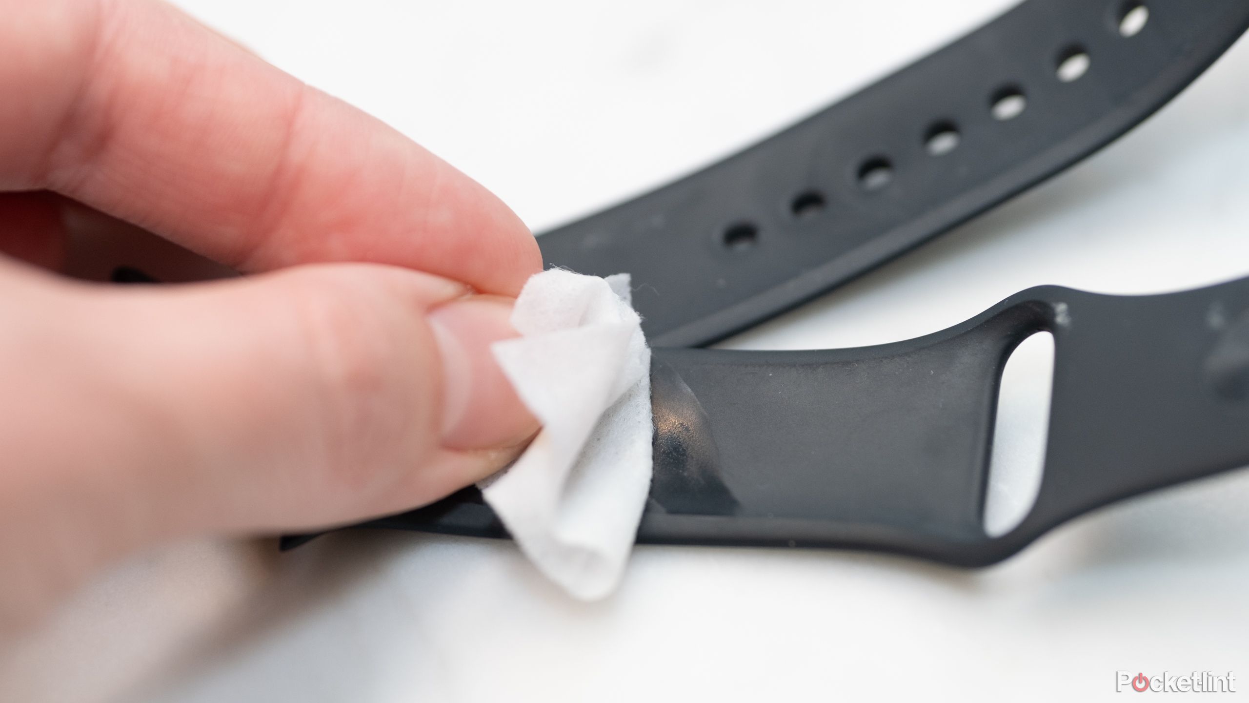 A photo of how to clean a smartwatch strap with an alcohol wipe.