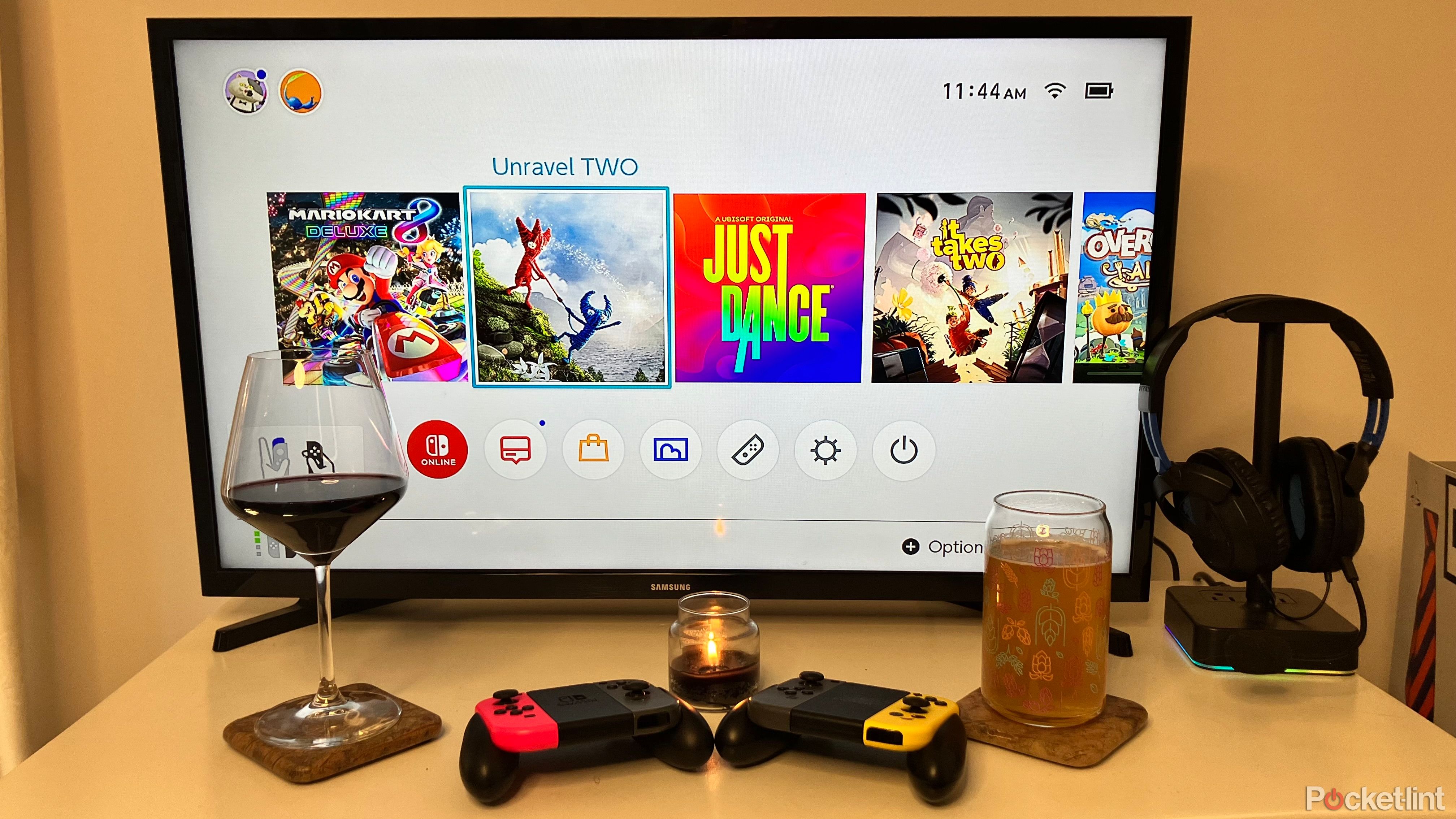 A Nintendo Switch controller in front of a gaming screen with wine, beer and candles