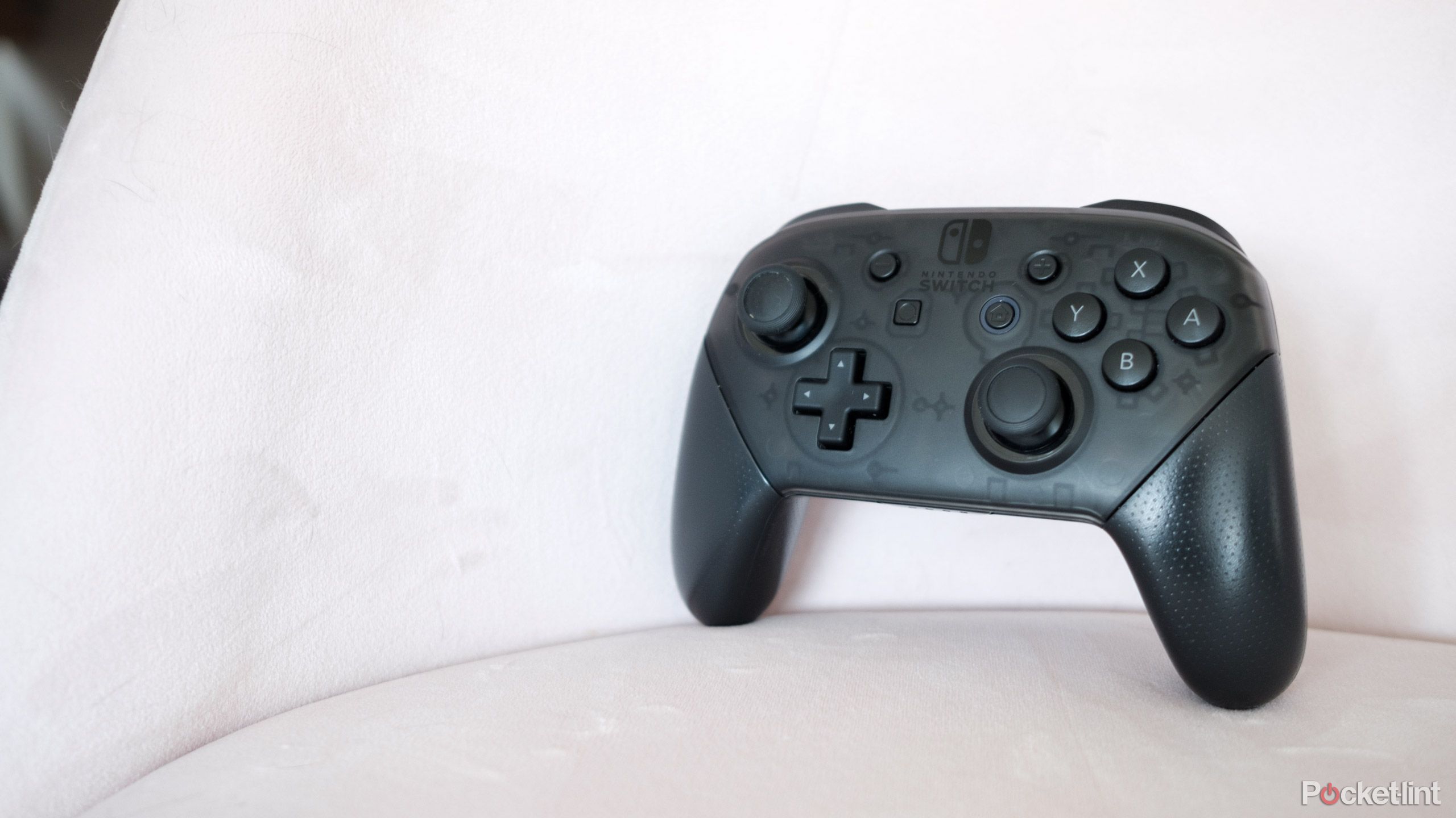 A Nintendo Switch Pro Controller on a pink chair