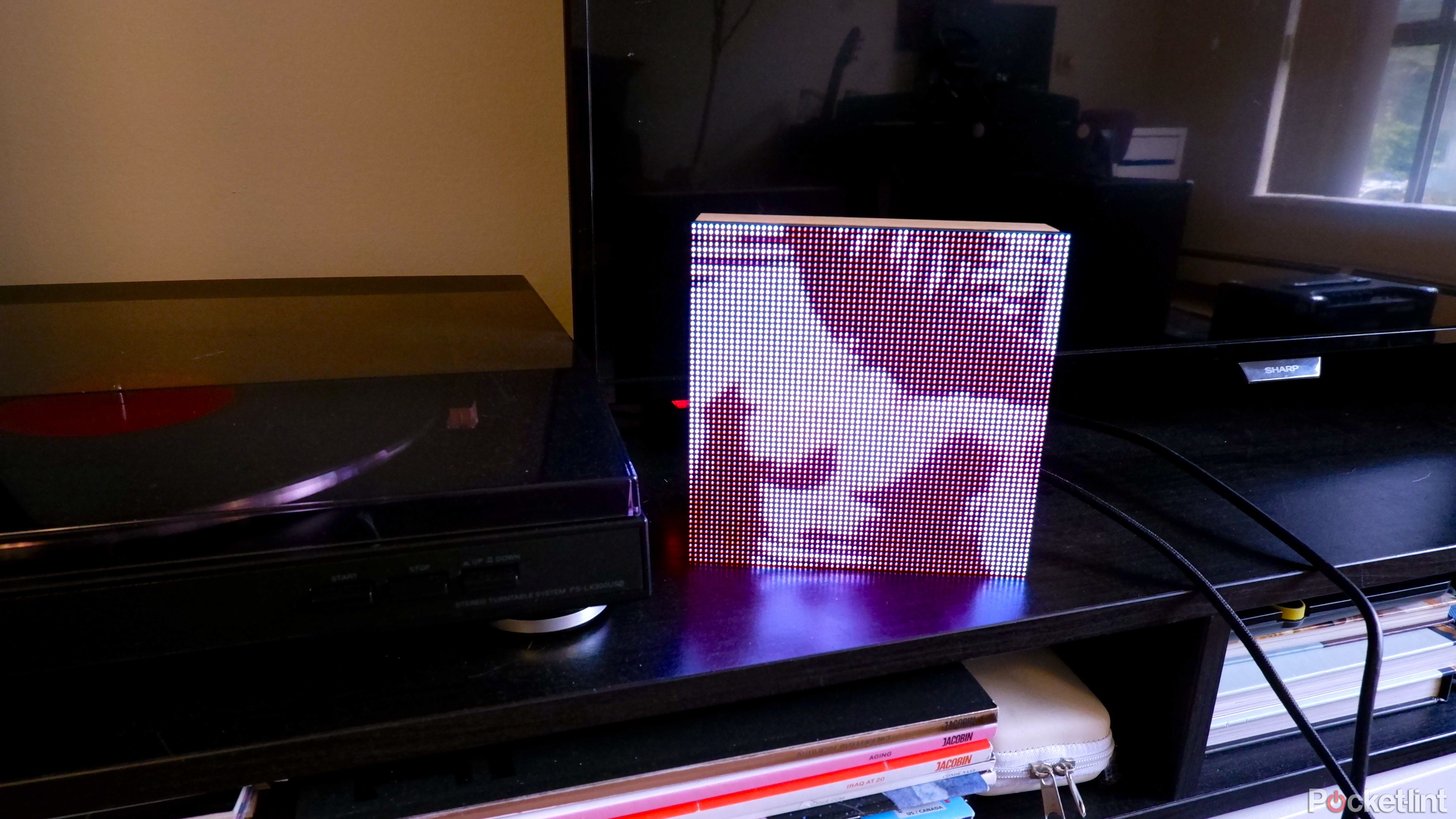A Tuneshine on a media console beside a TV and record player displaying The Smiths album art.