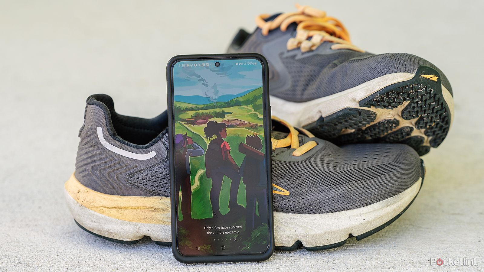 A phone displays the Zombies, Run! app while leaning against running shoes. 