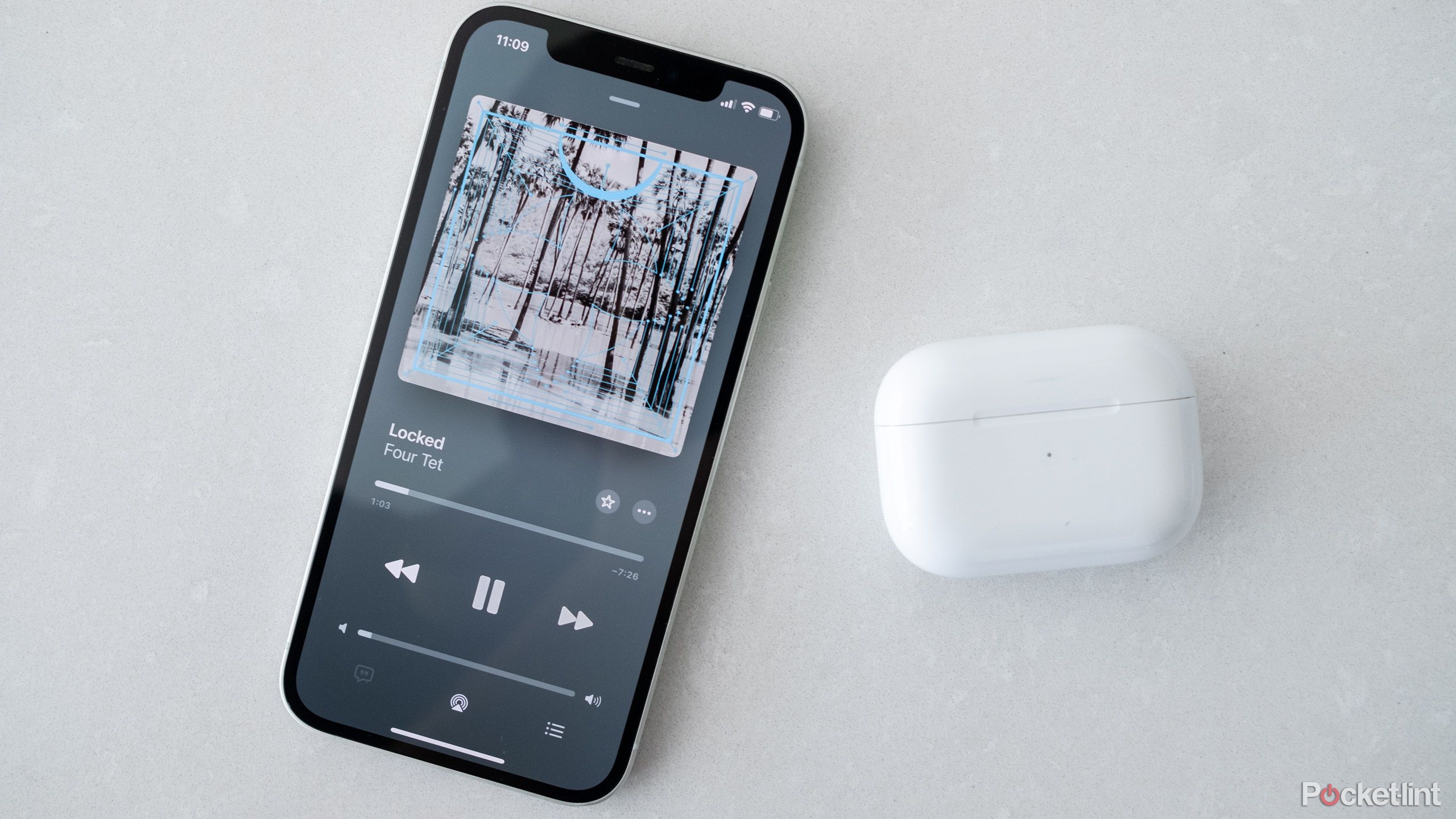 An iPhone 12 with Apple Music on the screen next to an AirPods Pro case