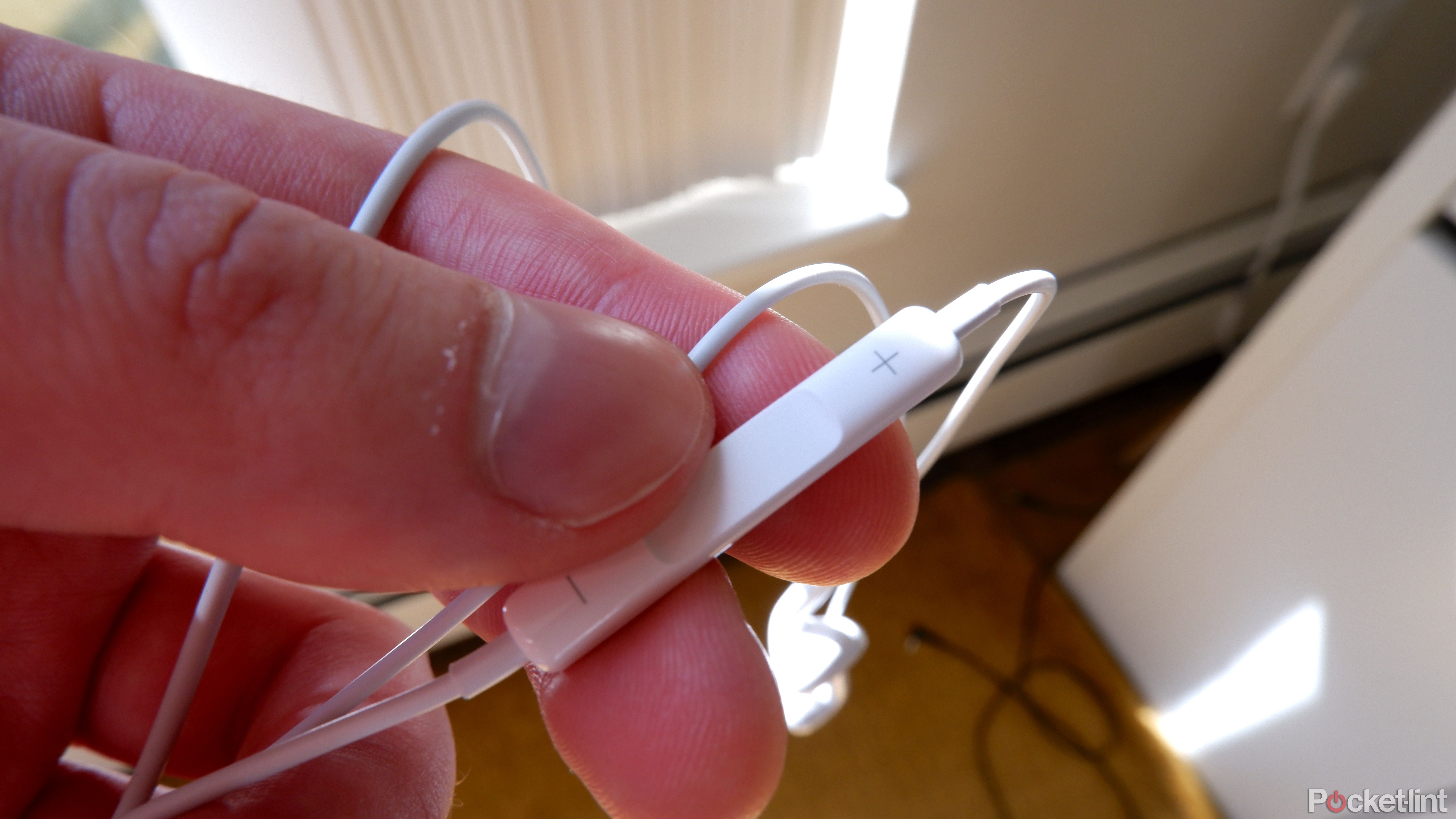 The in-line control part of the EarPods being held in a hand