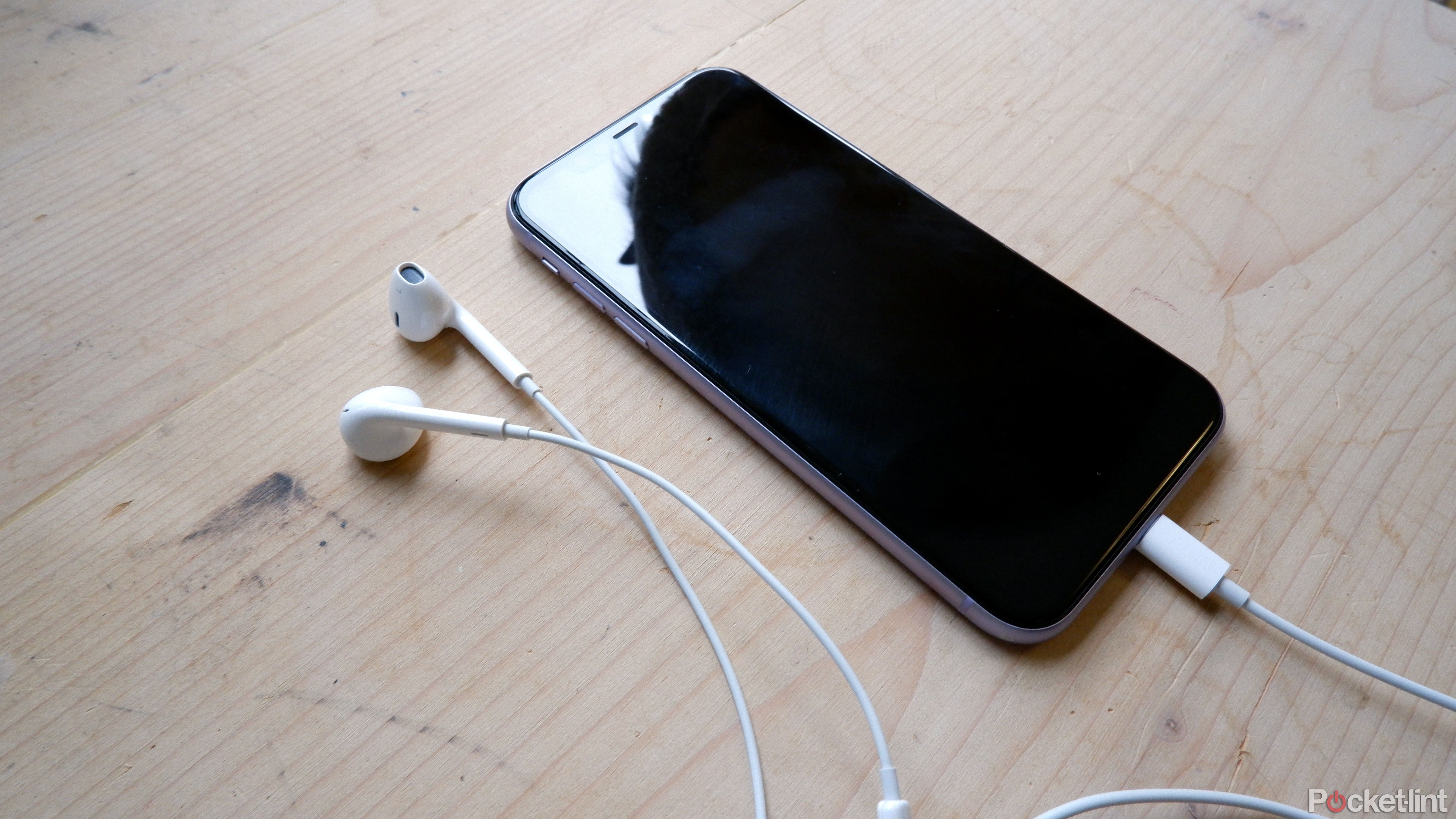Apple EarPods on a table connected to an iPhone