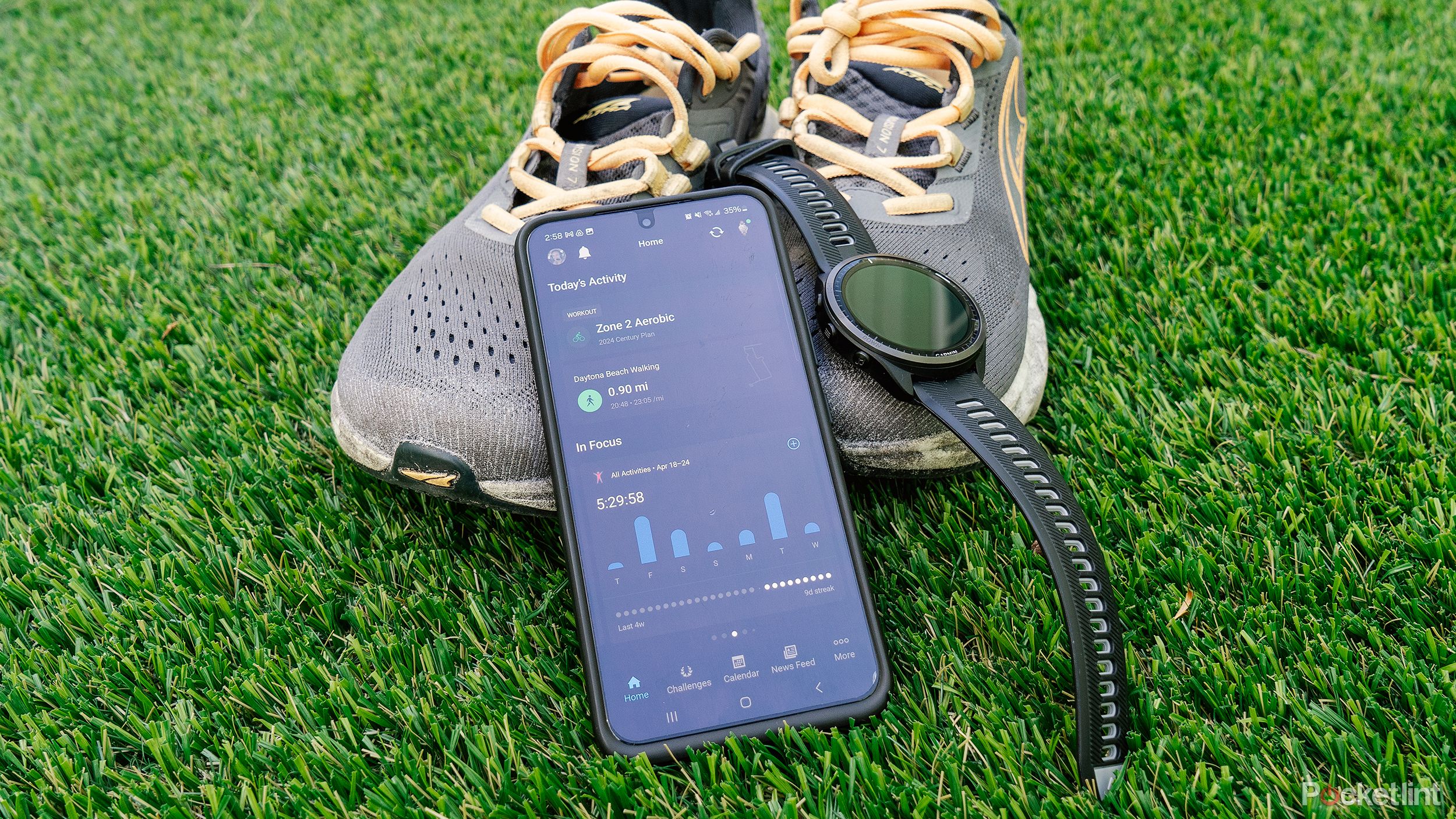 A phone with Garmin Connect displayed resting against running shoes with a Garmin Forerunner 965 watch. 