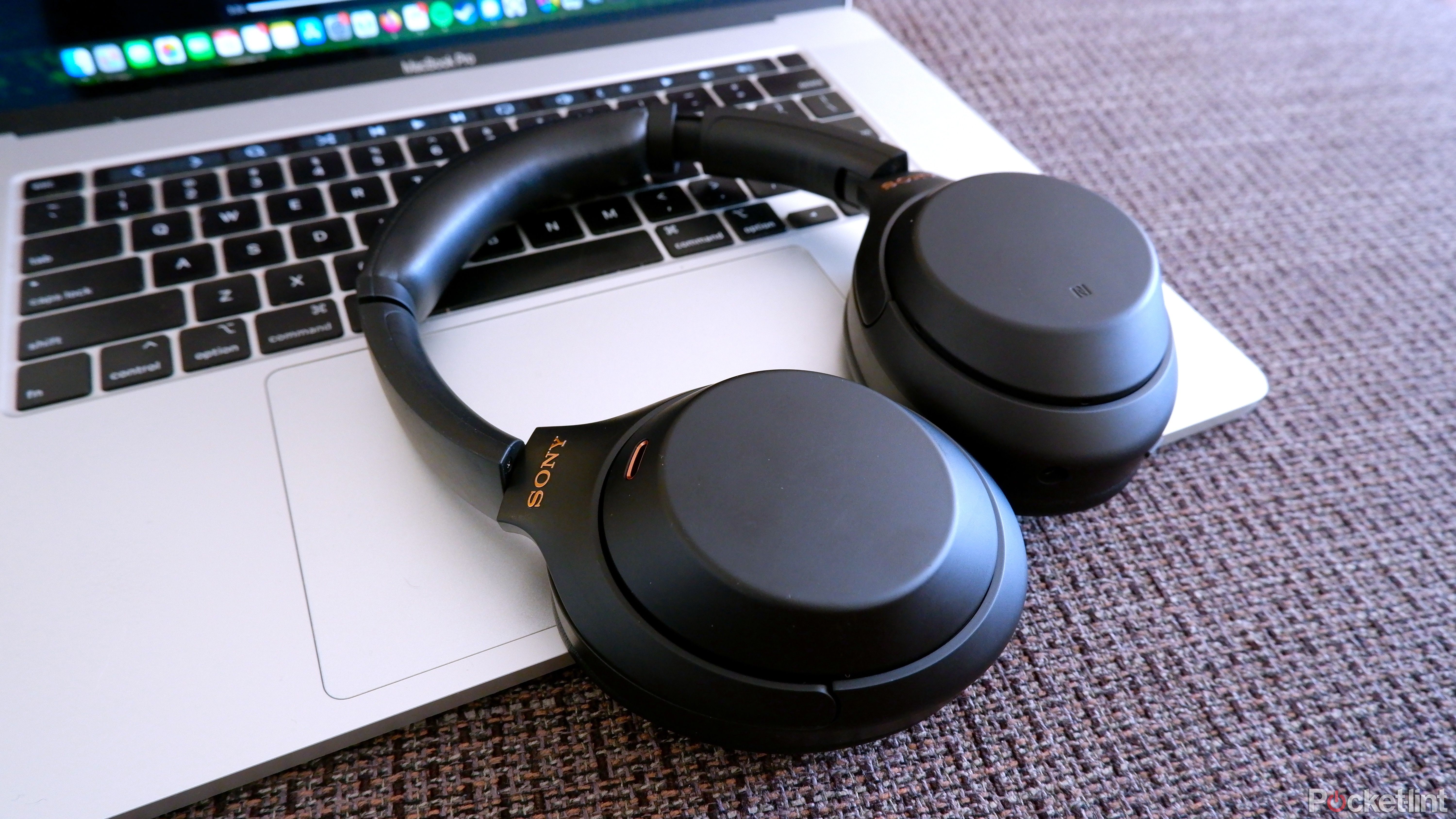 Sony WH-1000XM4 headphones resting on an open Macbook Pro laptop