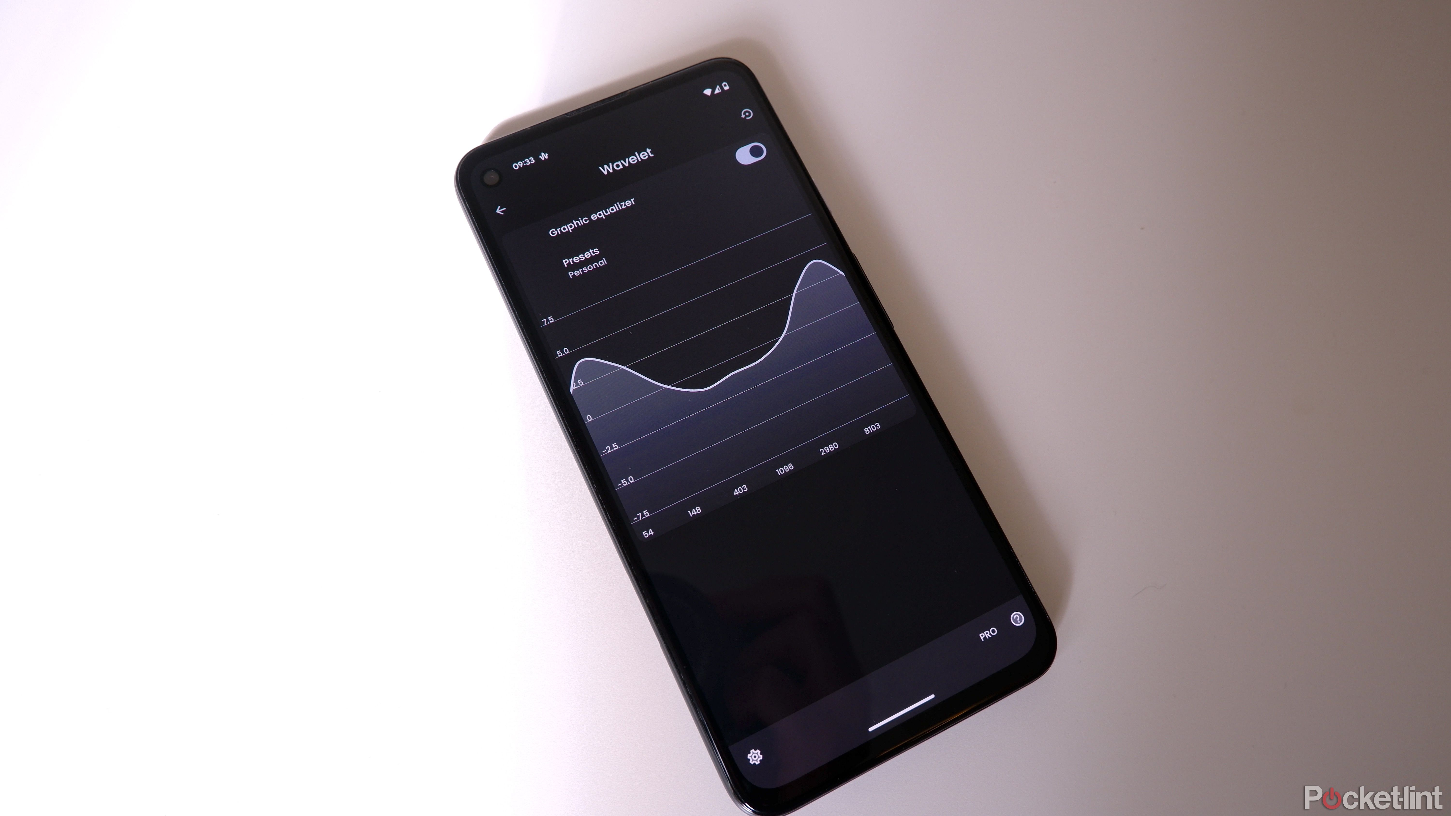 Un Google Pixel sur une surface blanche avec l'application Wavelet ouverte, affichant un égaliseur personnalisé.