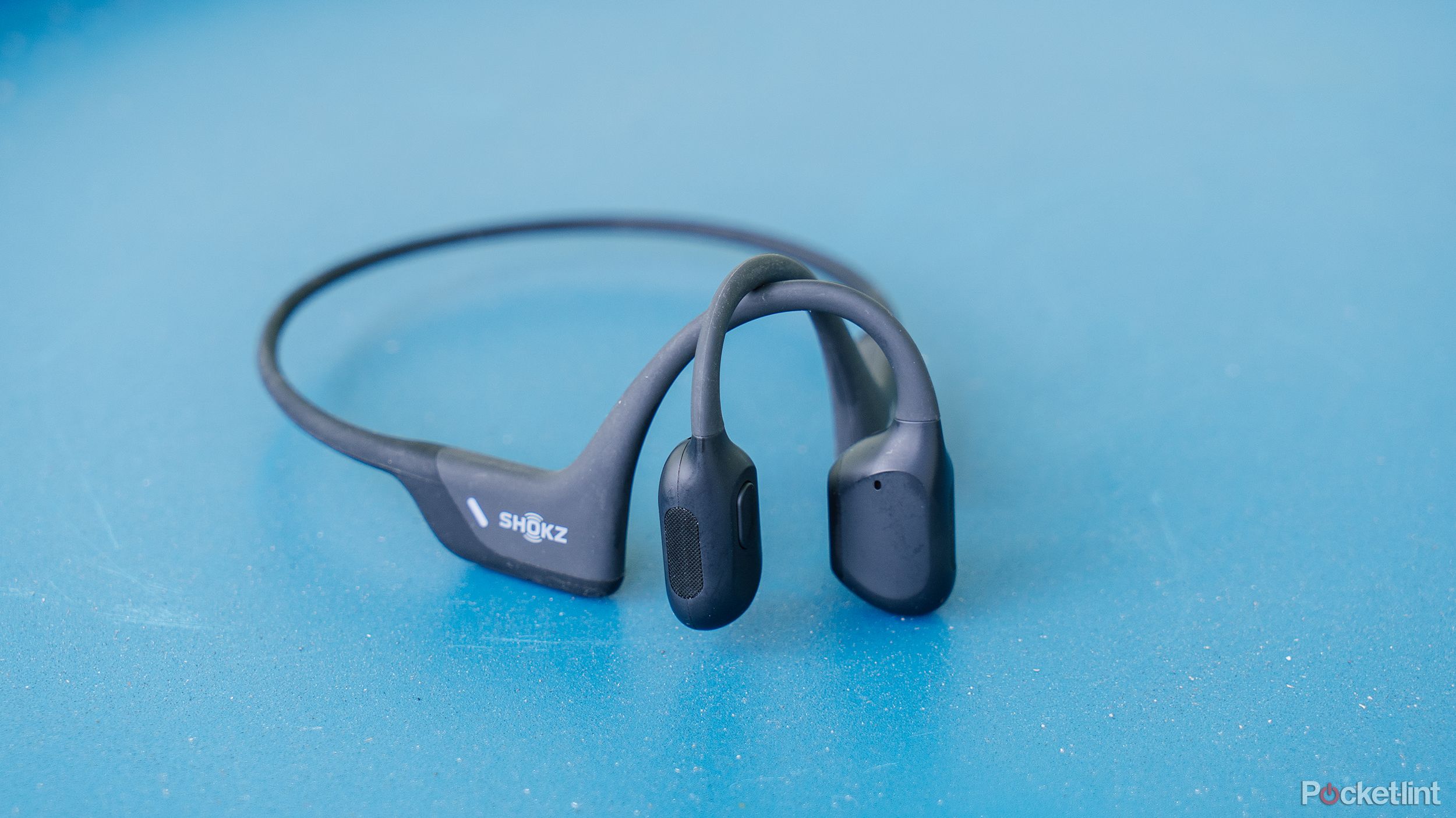 Shokz Open Run Pro bone conduction headphones on a blue table. 
