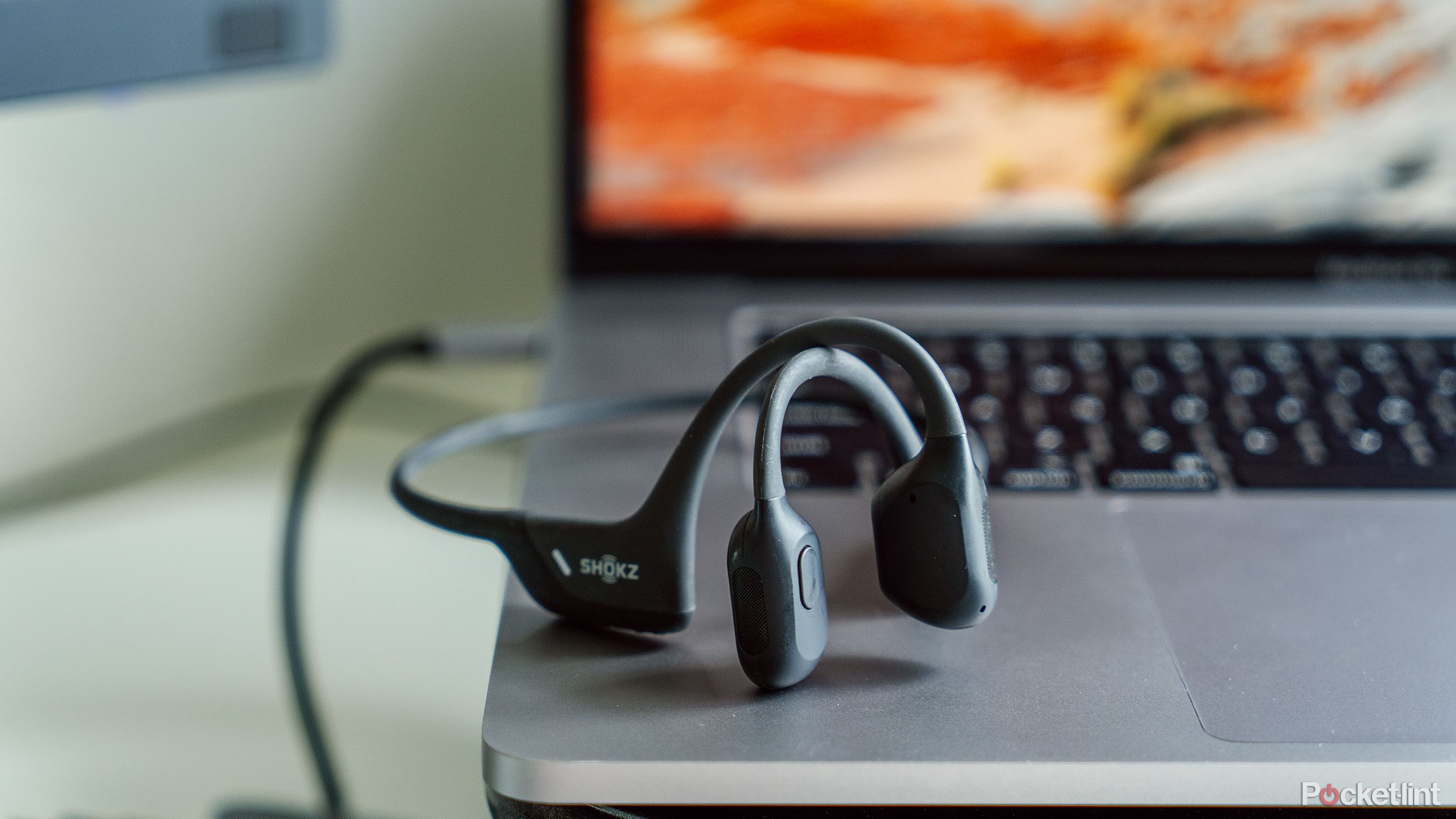A pair of SHokz Open Run Pro bone conduction headphones on a MacBook Pro laptop. 