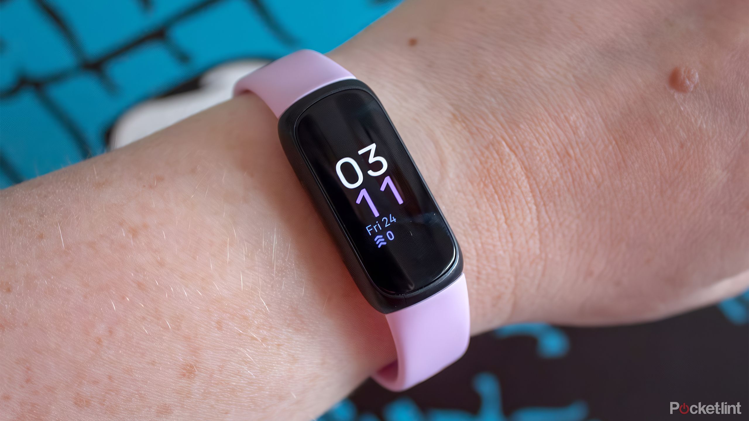 Tje pink Fitbit Inspire 3 fitness tracker on a wrist. 