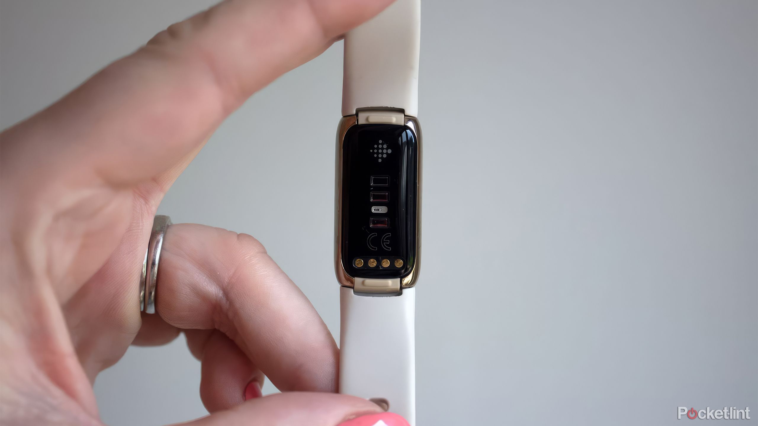 A woman holds a Fitbit Luxe in her hand