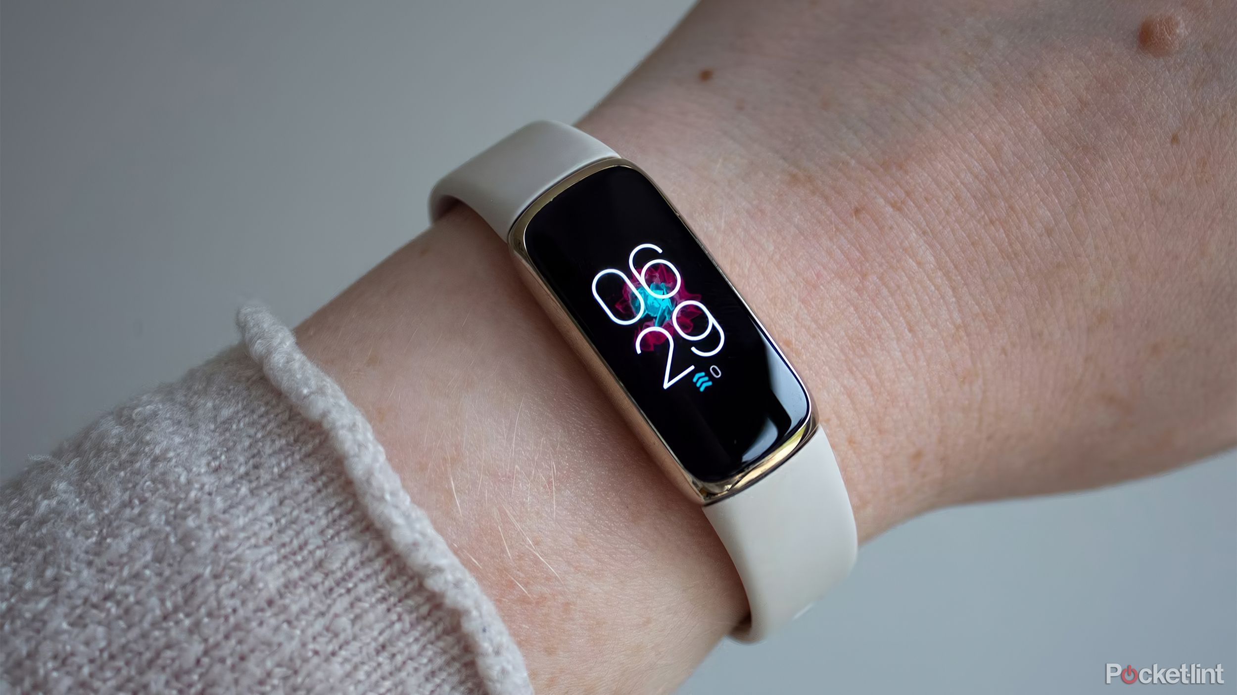 The Fitbit Luxe on a wrist in front of a white wall. 