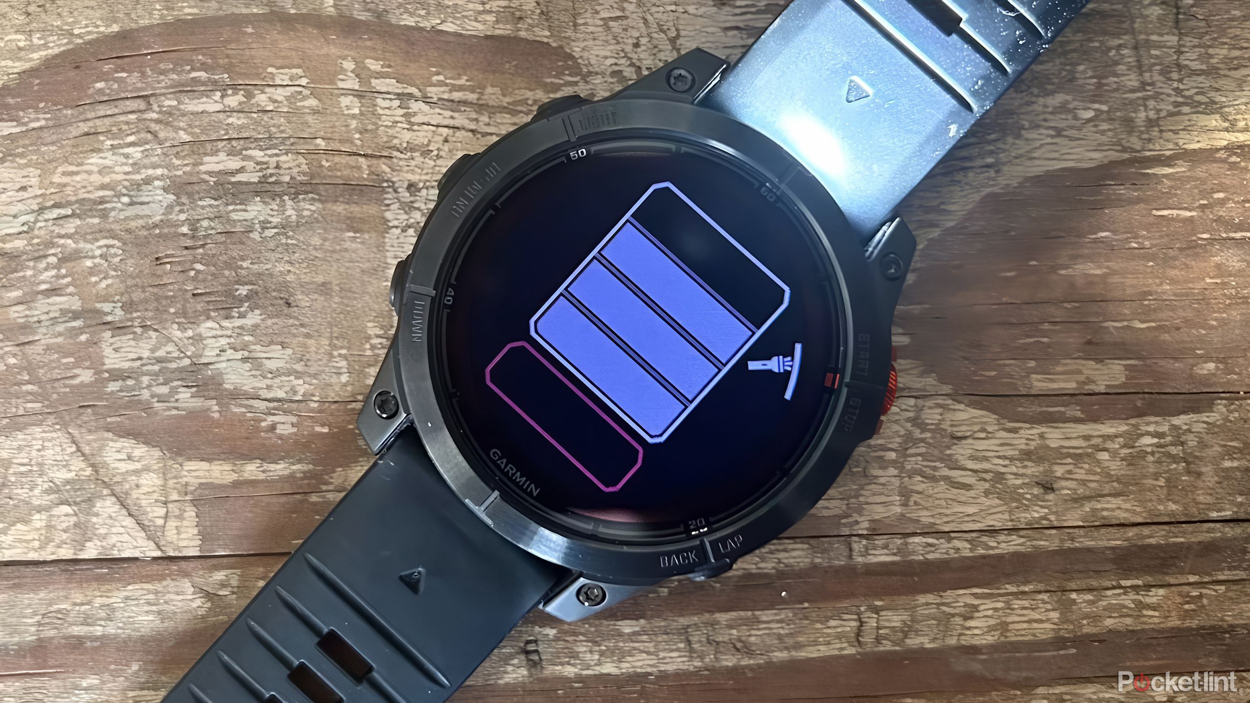 The Garmin fenix 7 Pro with the flashlight turned on is set on a wood table.