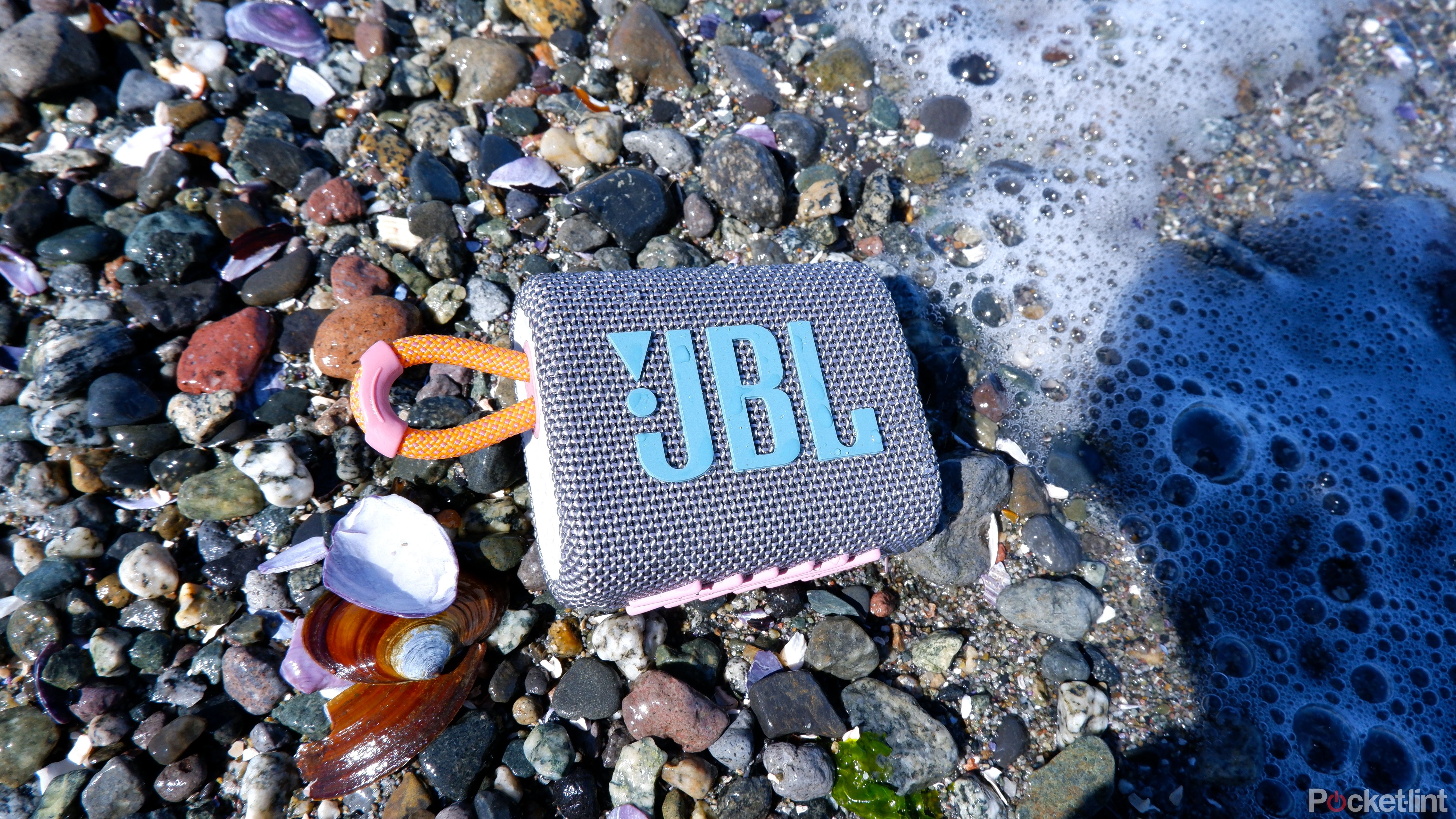 JBL Go 3 set down among rocks and shells with sea water on the right side