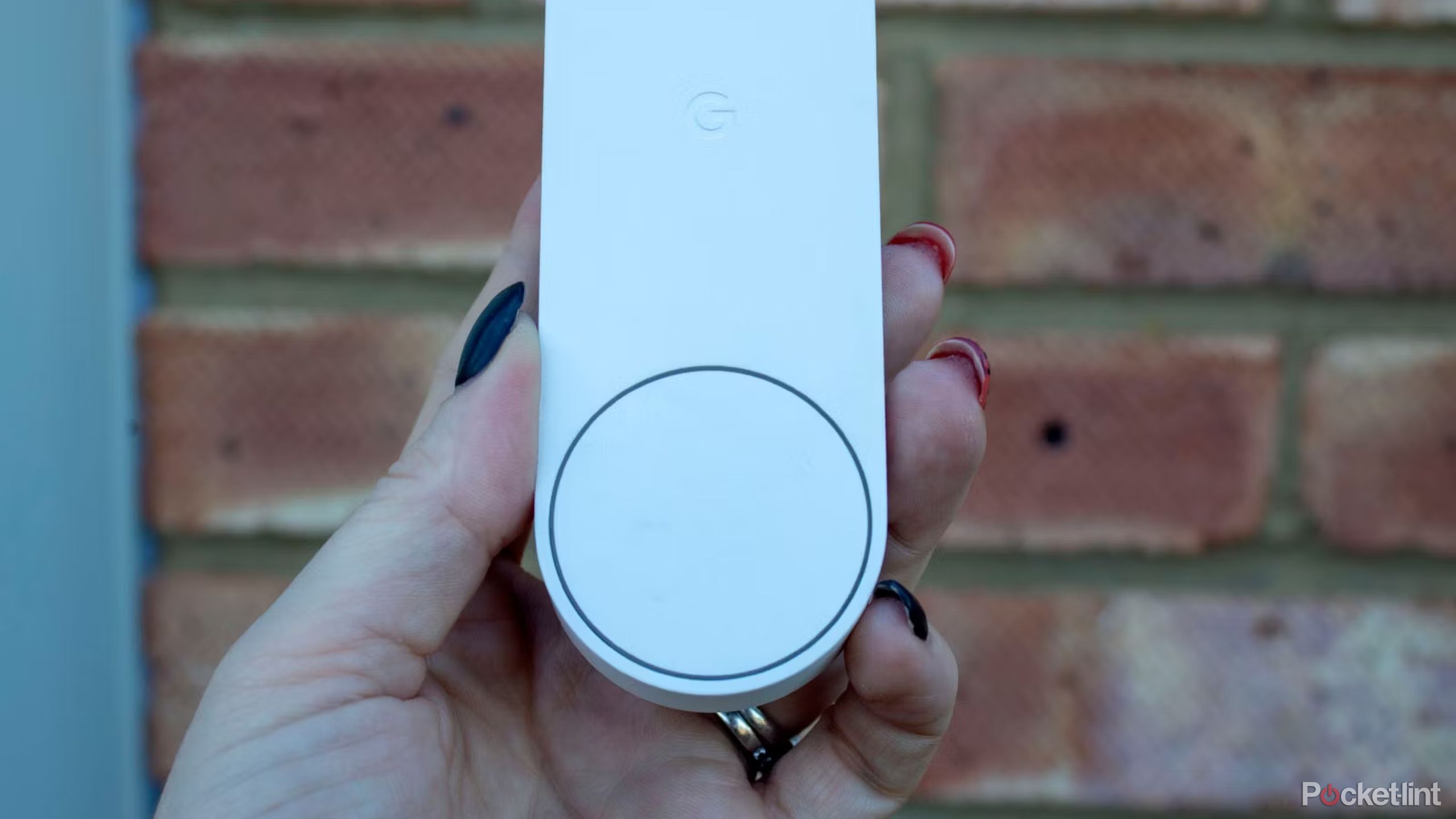 Someone holding the Nest Battery Doorbell against a brick wall. 