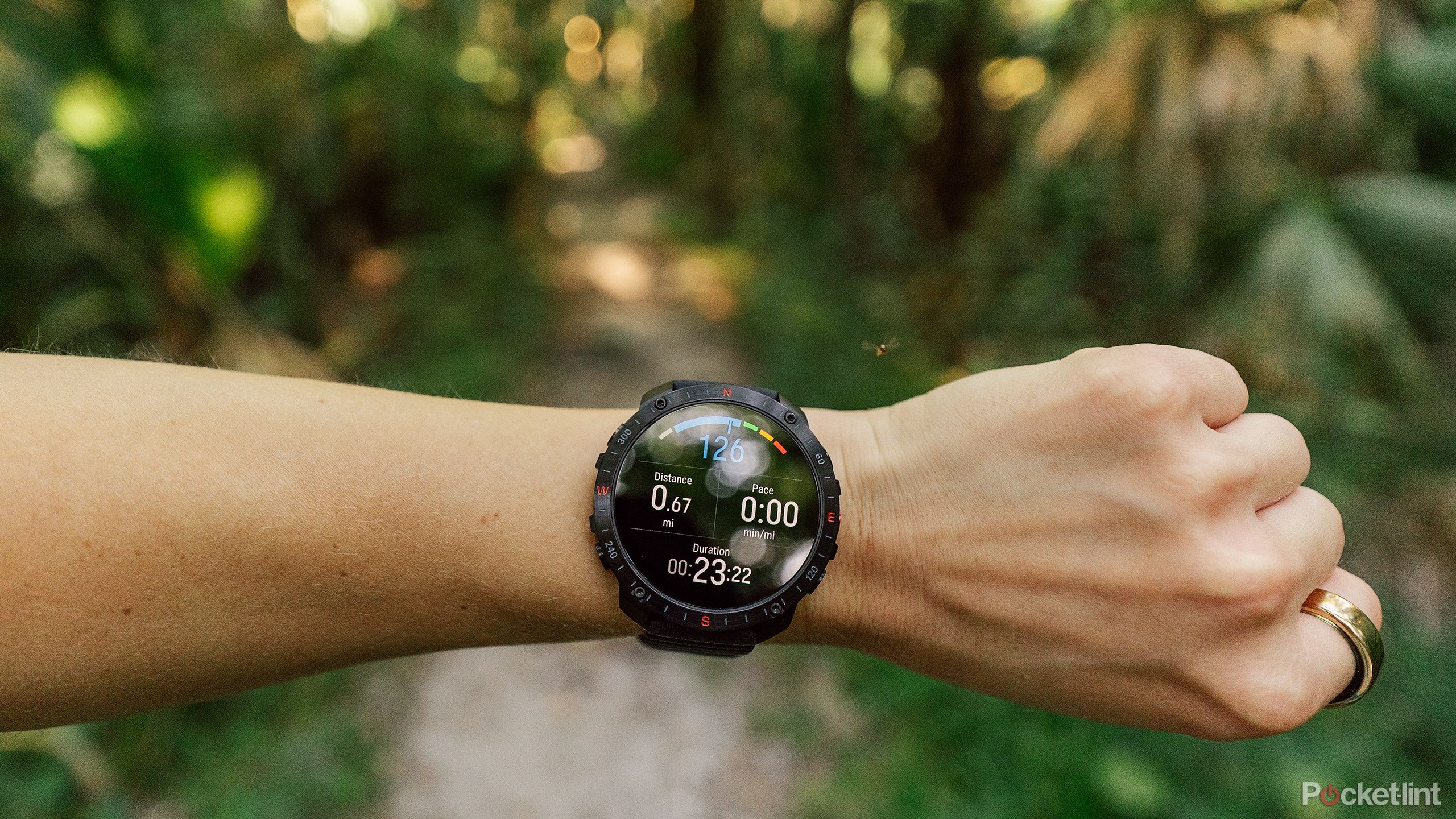 The Polar Grit X2 Pro on a wrist in front of a blurred trail. 