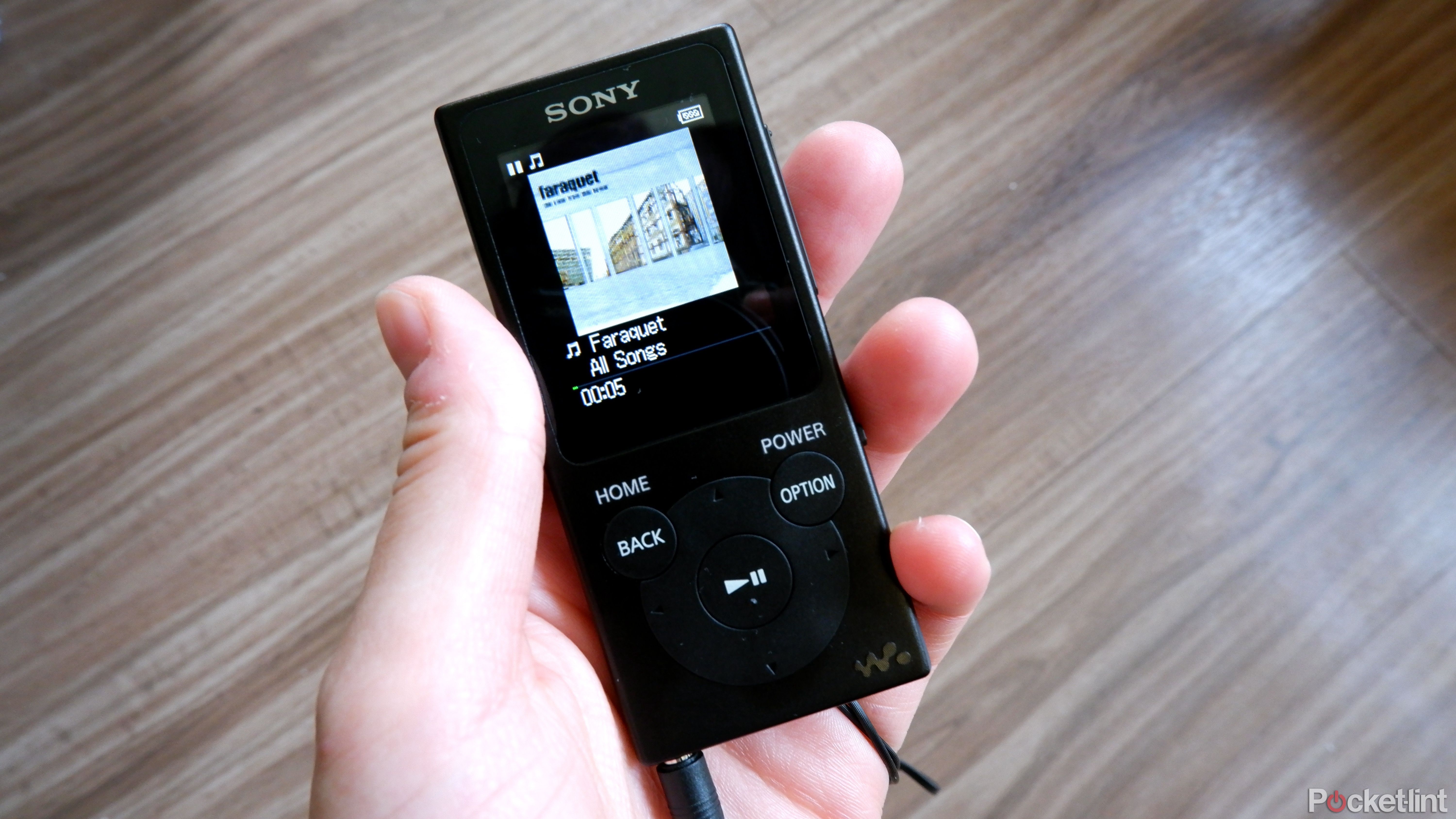 A Sony Walkman being held in a hand with a song playing.