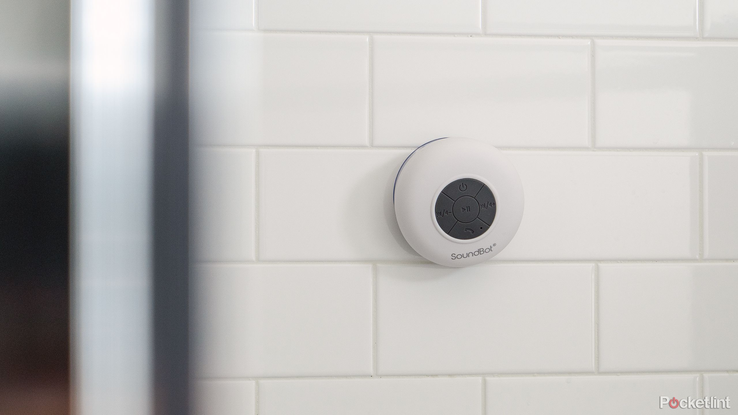 The white Soundbot SB510 on a white tile shower wall.
