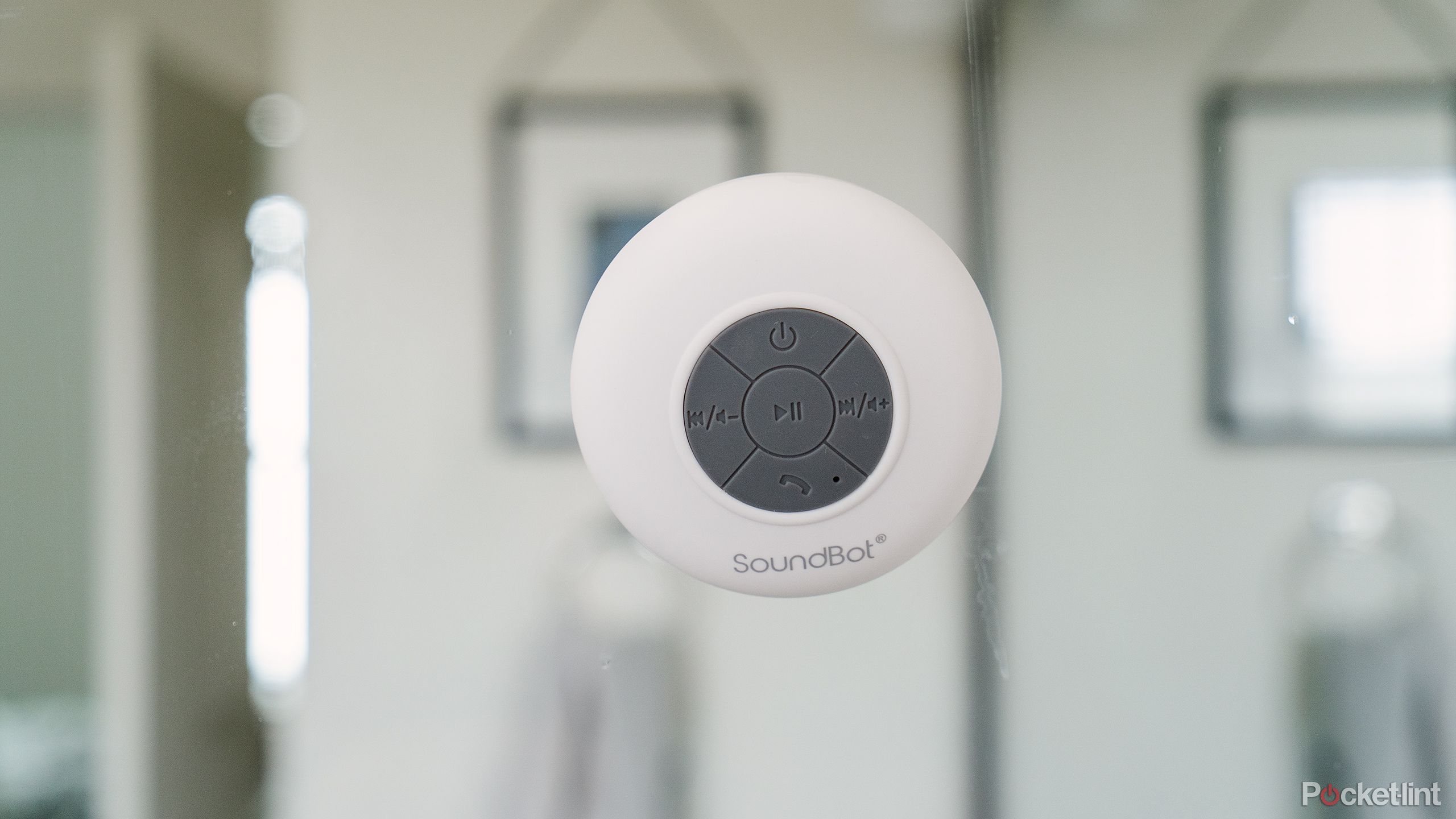 The white Soundbot SB510 on a glass shower wall.