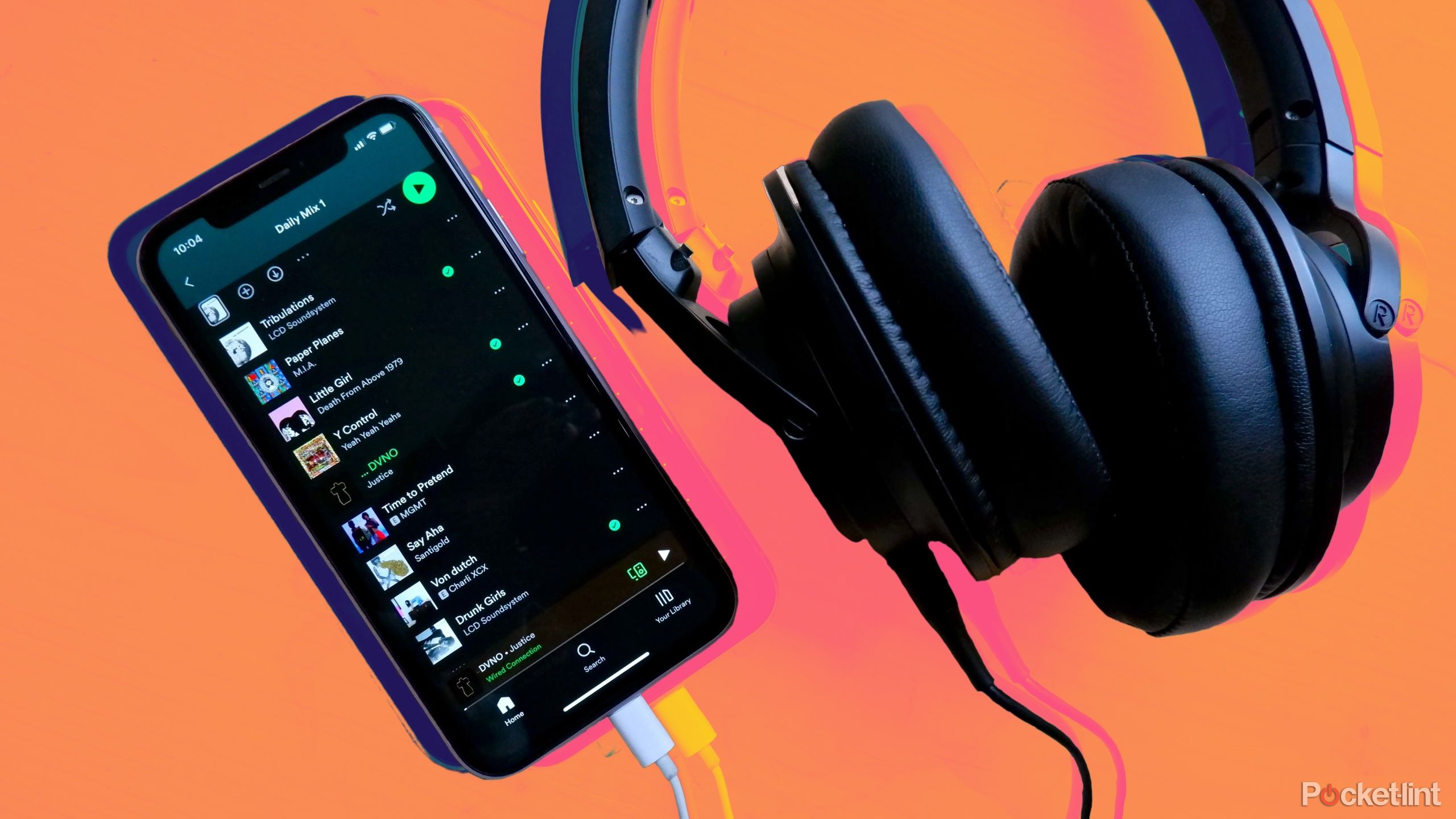 An iPhone with Spotify open with a pair of headphones plugged in