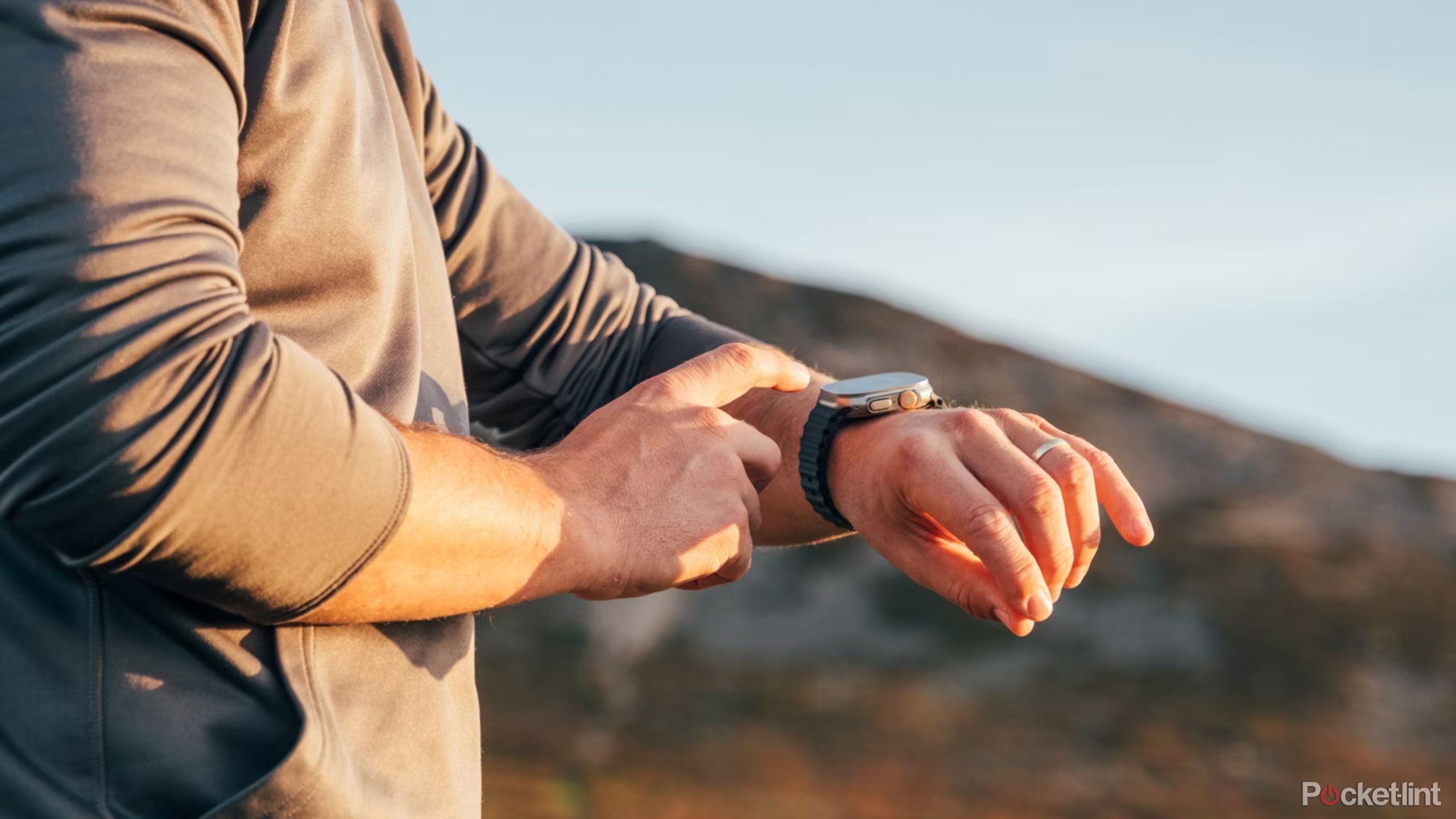 A person wearing an Apple Watch Ultra 2 at sunset