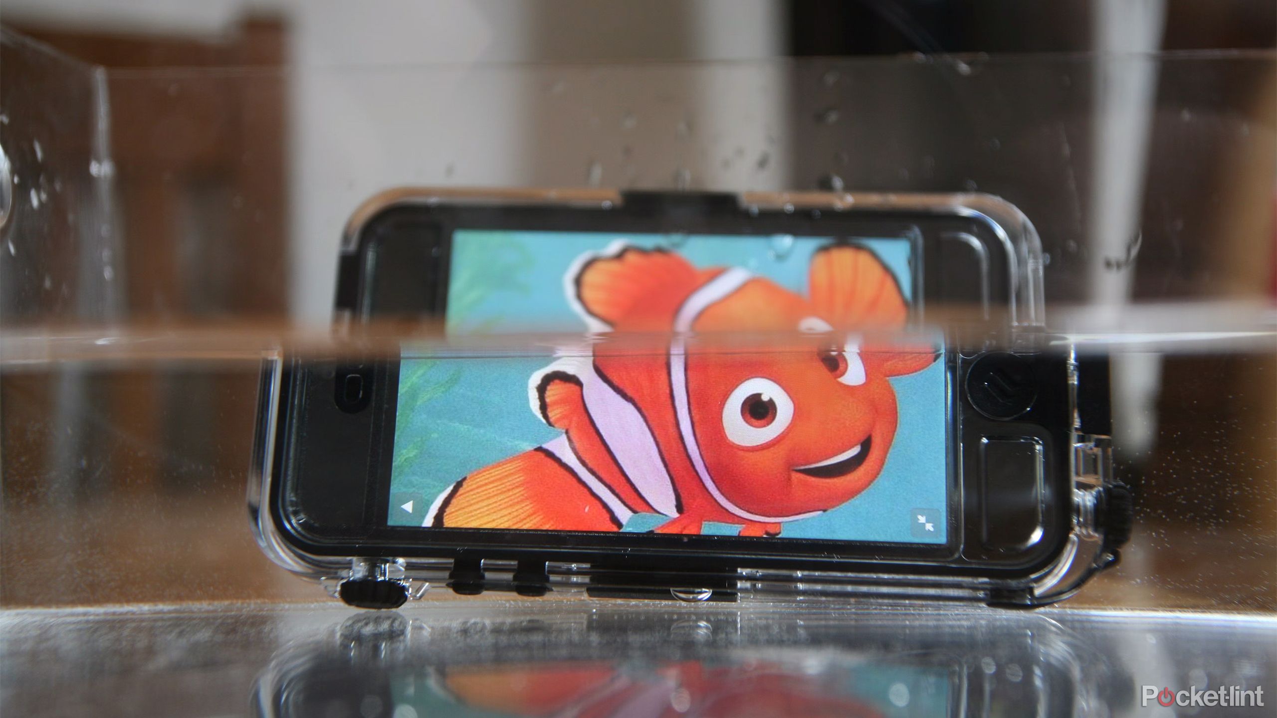 A phone with Nemo on the display sits partially submerged in a tank of water. 