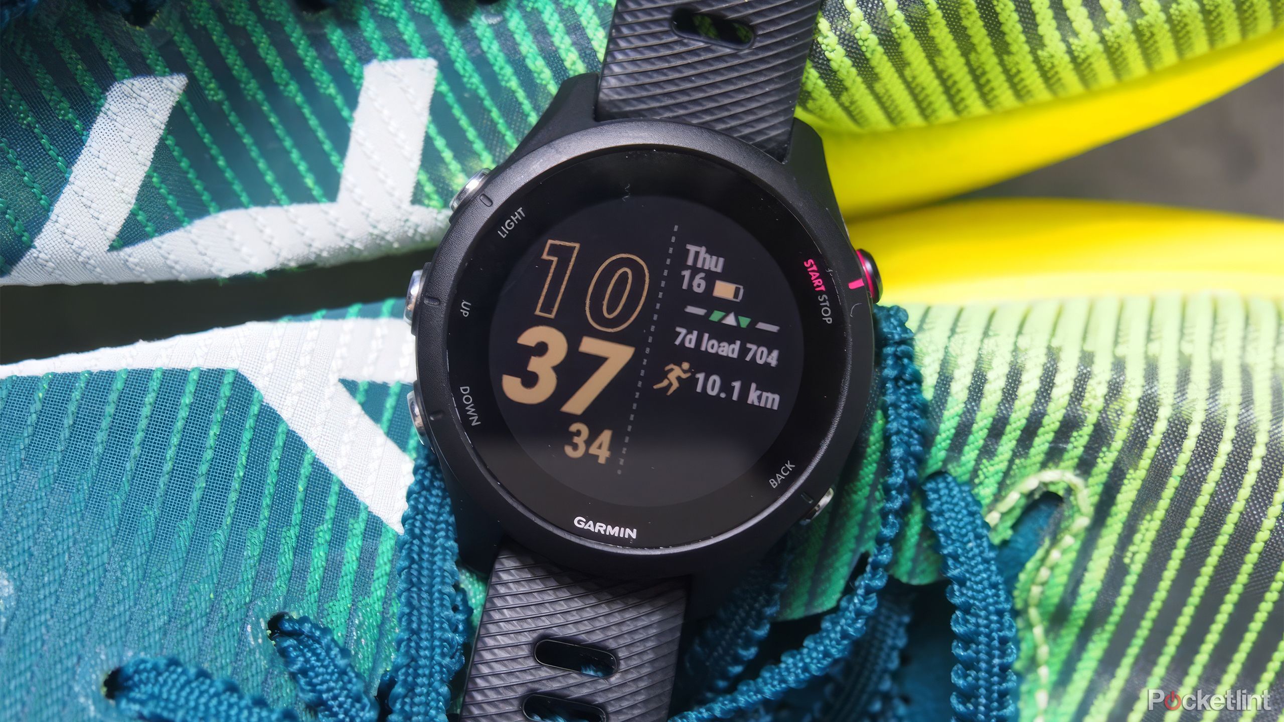 The Garmin Forerunner 255 on a green, yellow, and blue pair of running shows. 