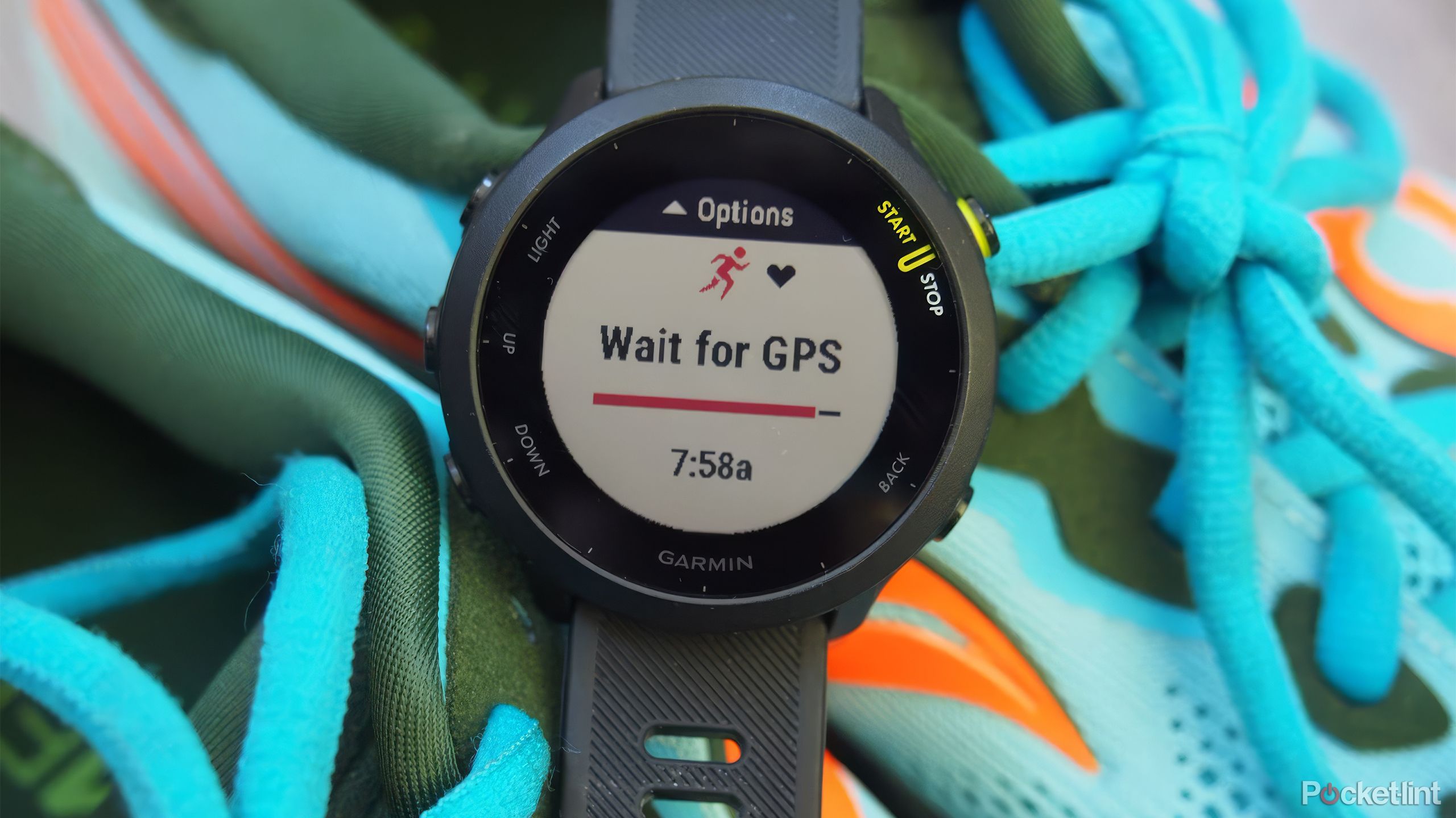 The Garmin Forerunner 55 on a pair of blue, green, and orange running shoes. 