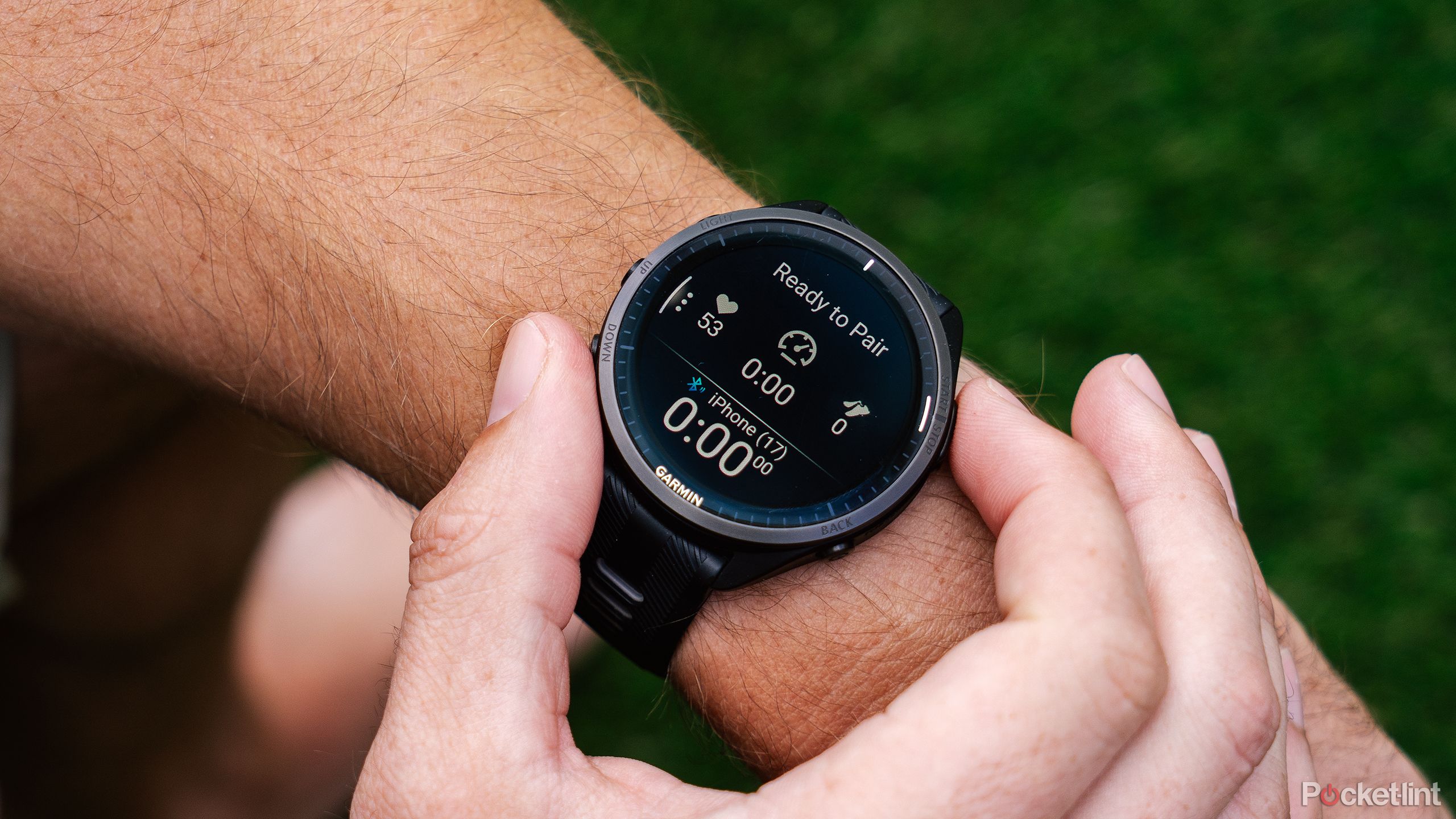 A hand presses buttons on the Garmin Forerunner 965 while it's on a wrist. 