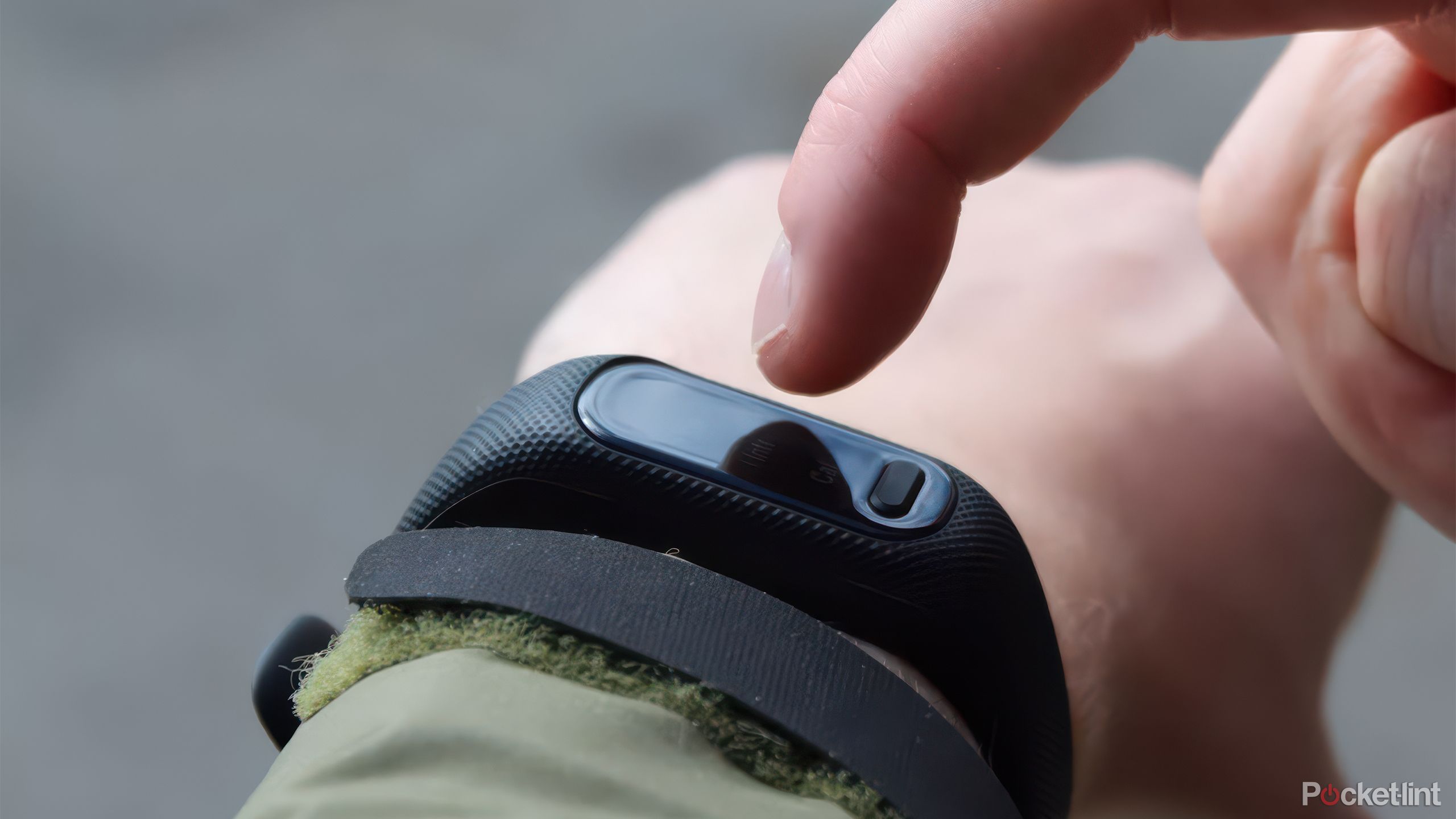 The Garmin vivosmart 5 on a wrist with a finger hovering over it. 