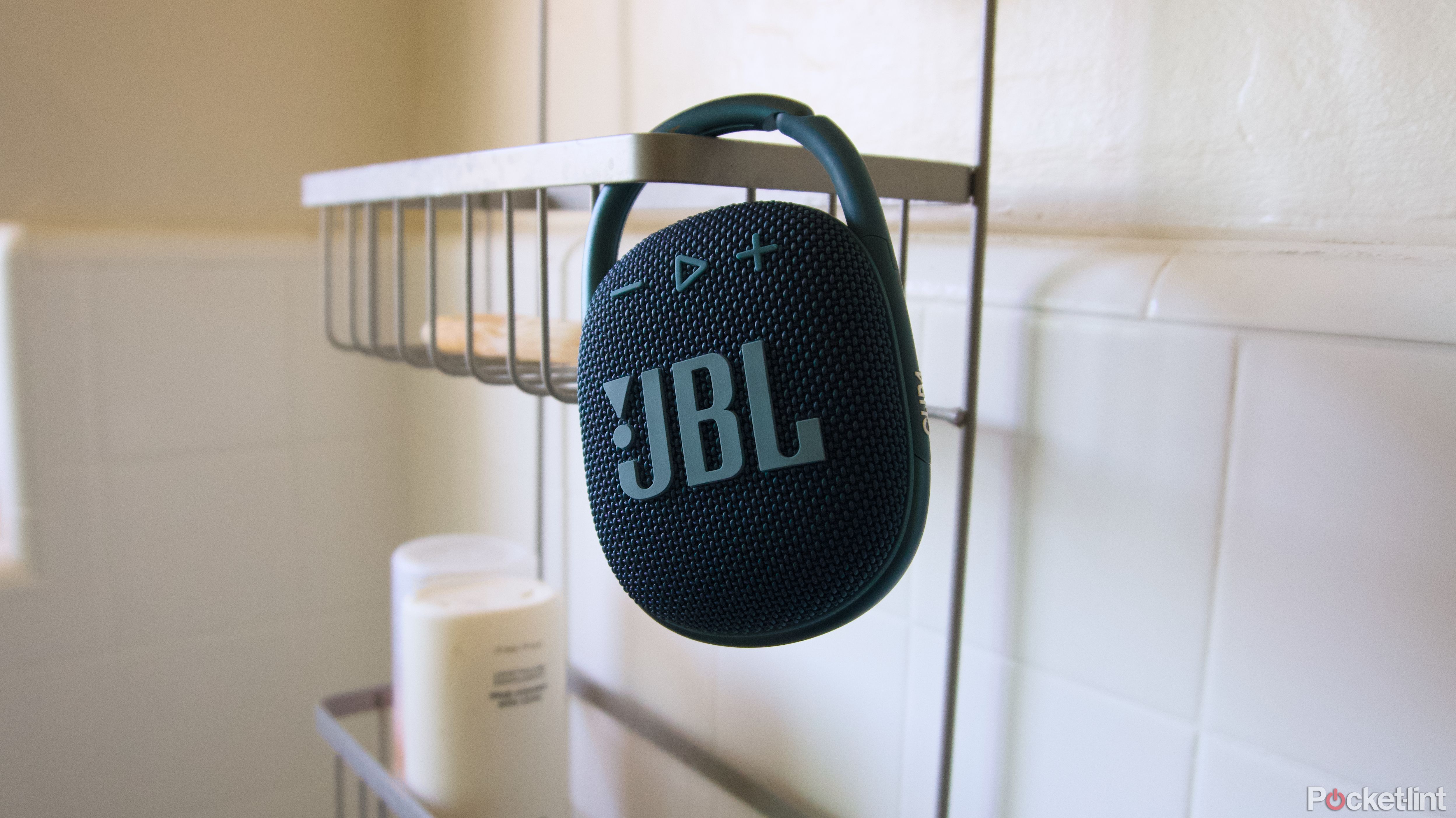 A round JBL Clip 4 attached to a shower caddy.