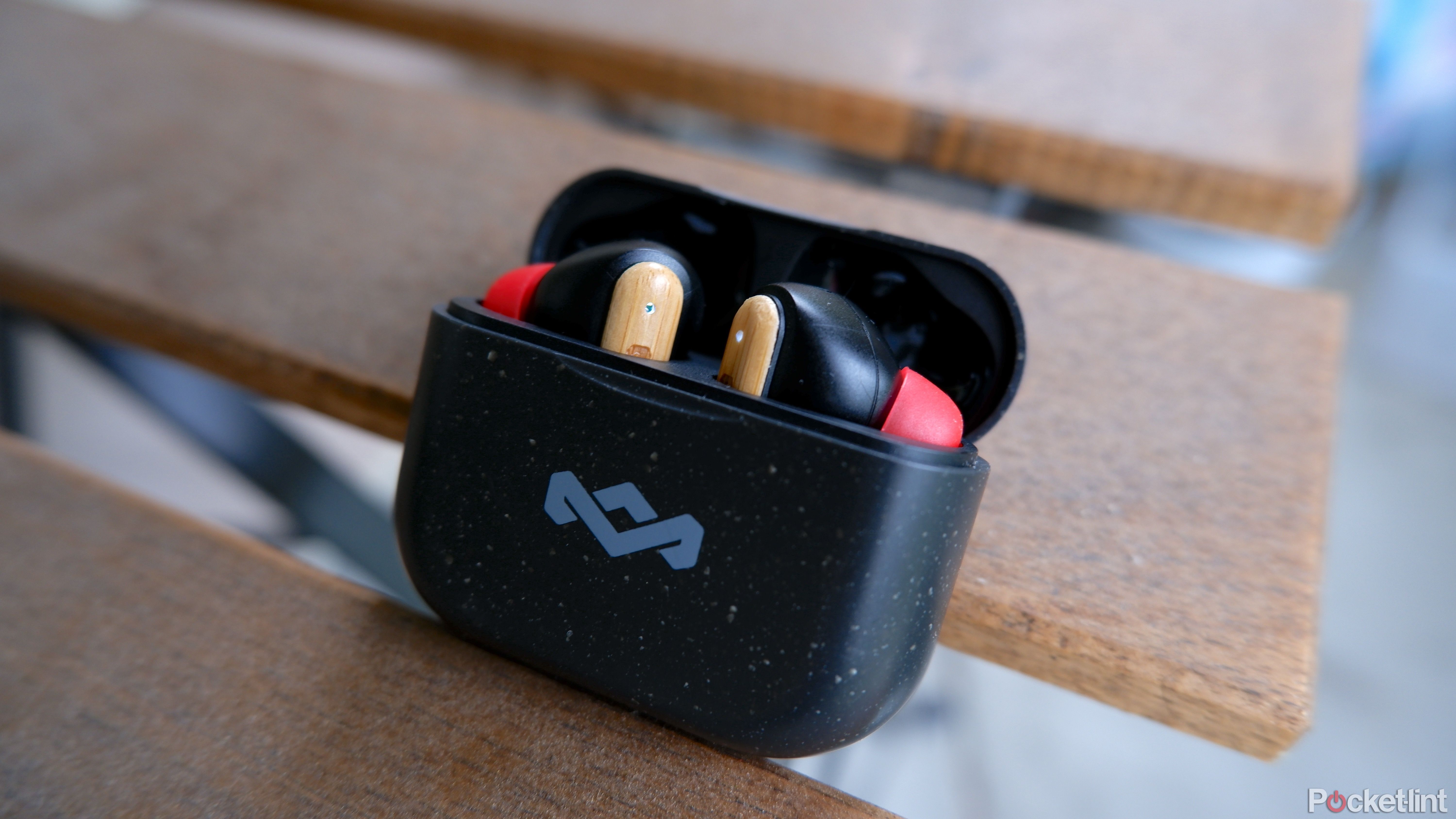 The House of Marley Little Bird earbuds inside their case resting on a patio table outdoors