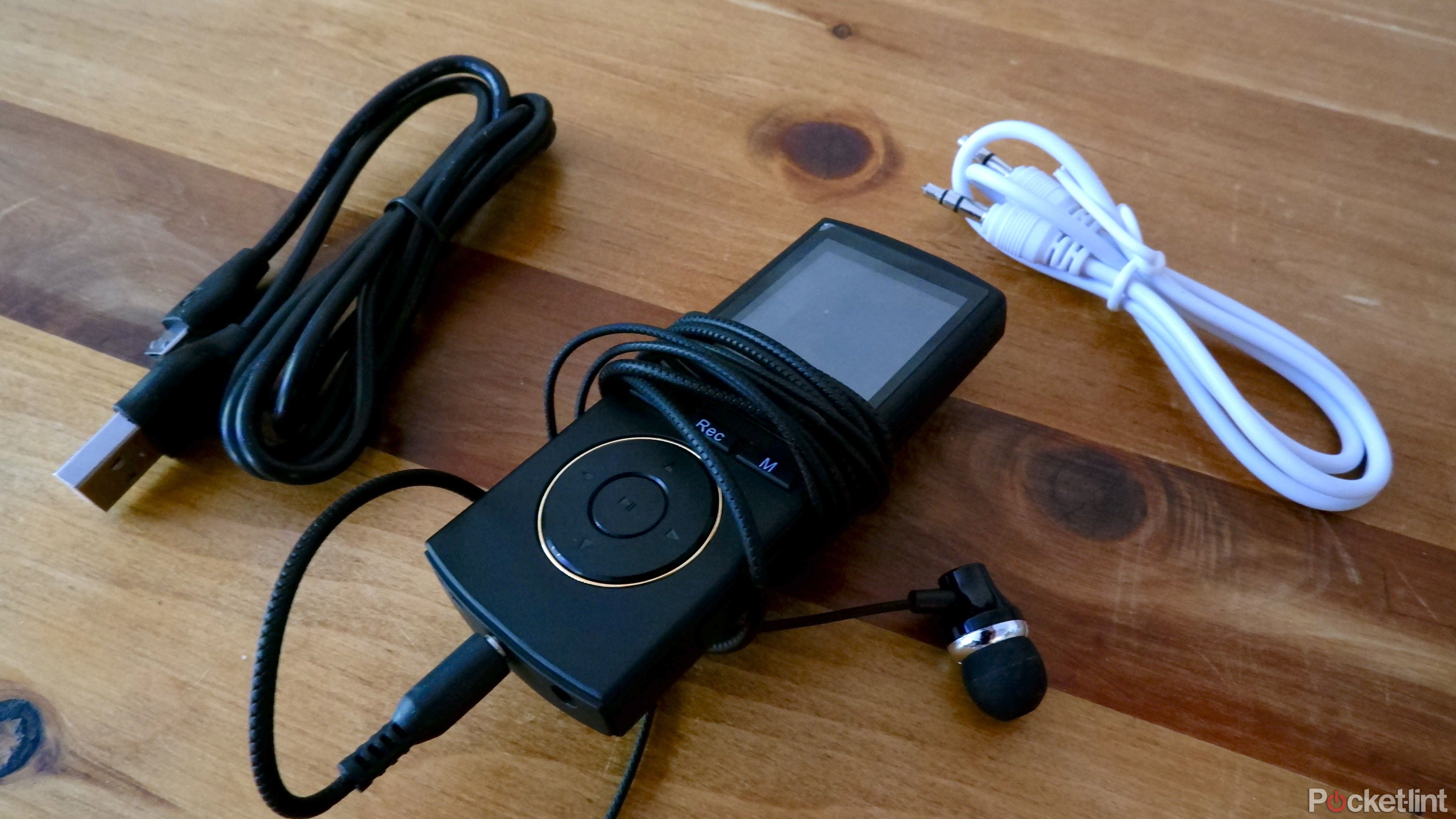 The Safuciiv MP3 player with the included earbuds plugged in, alongside the line-in cable and microUSB cable.