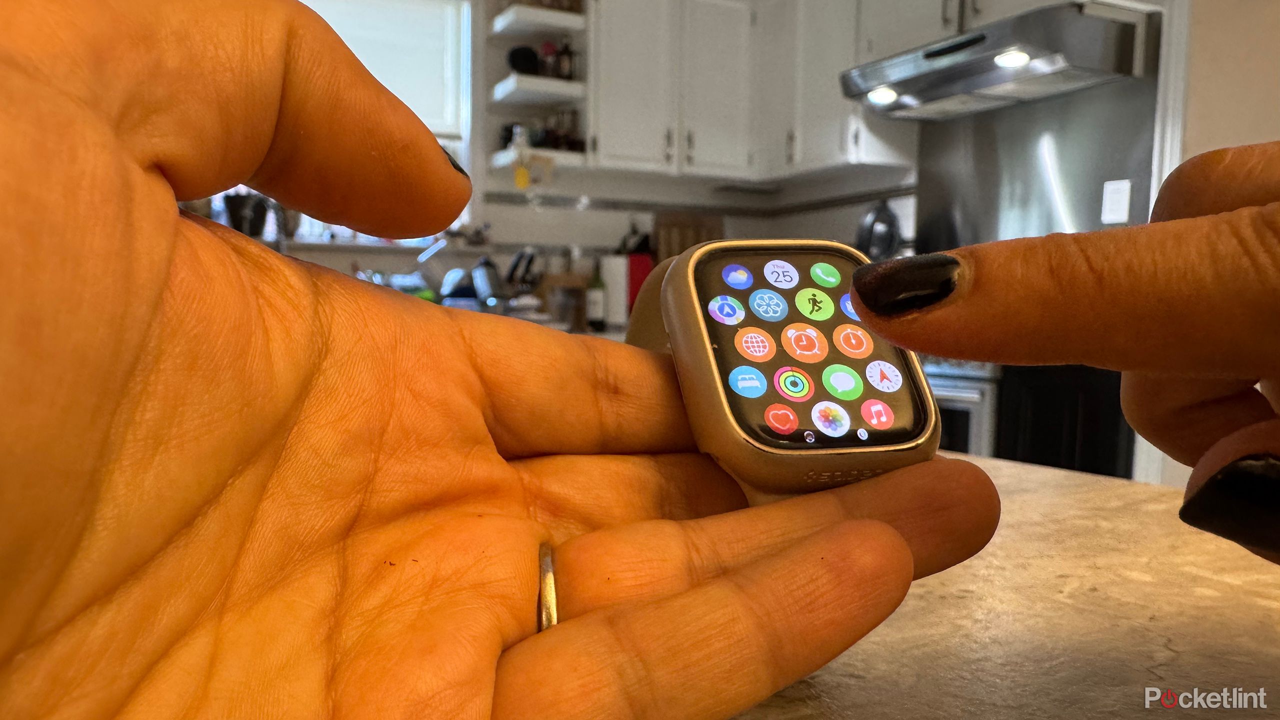 An Apple Watch in hand with a finger touching an icon on the home screen.