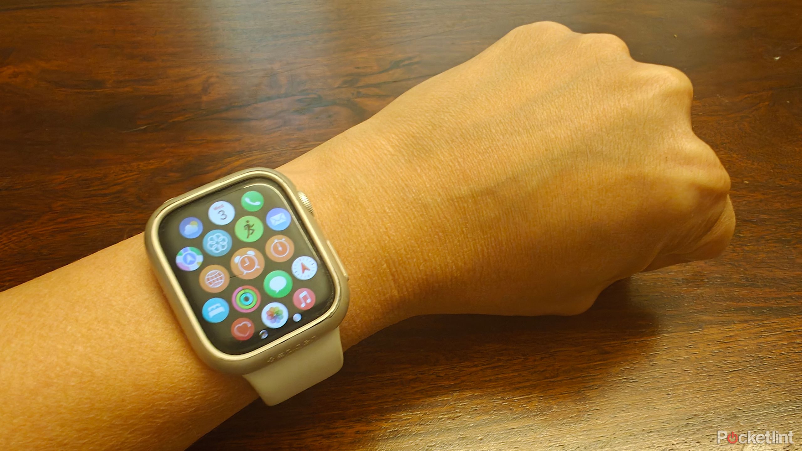 An Apple Watch showing app icons and a hand clenching a fist.